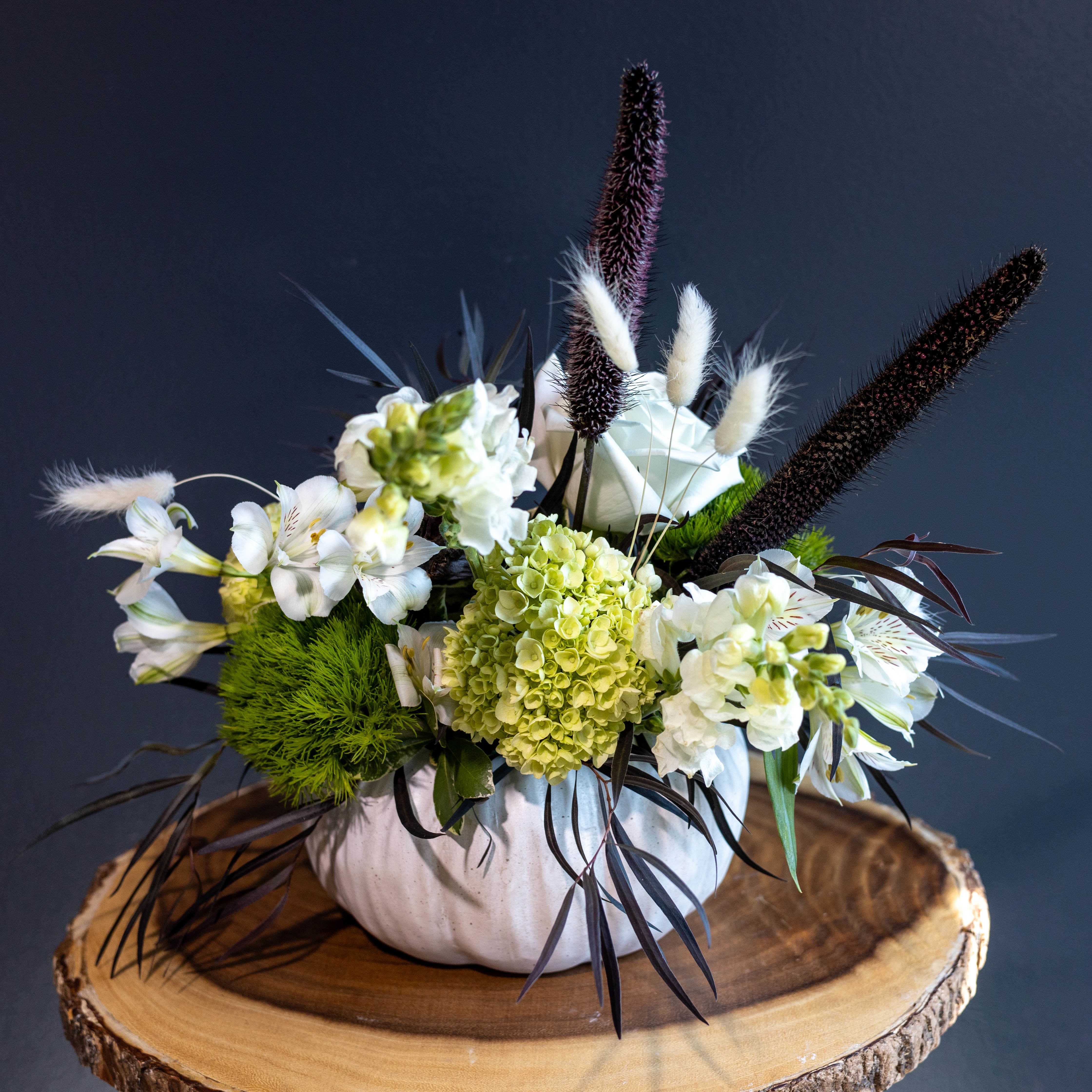Casper's Garden - Not all ghosts are scary, some have great taste in flowers.  Casper’s Garden is a hauntingly elegant arrangement of all-white blooms nestled in a charming white ceramic pumpkin vase. With soft hydrangeas, crisp alstroemeria, and ghostly white roses paired with deep, moody textures and pops of eerie greenery, this design brings a perfectly spooky-chic vibe to your Halloween decor.  Whether you’re hosting a haunted dinner party, decorating your entryway for trick-or-treaters, or gifting a little seasonal magic, Casper’s Garden adds a ghostly glow without the fright.  Playful. Sophisticated. Slightly supernatural. 