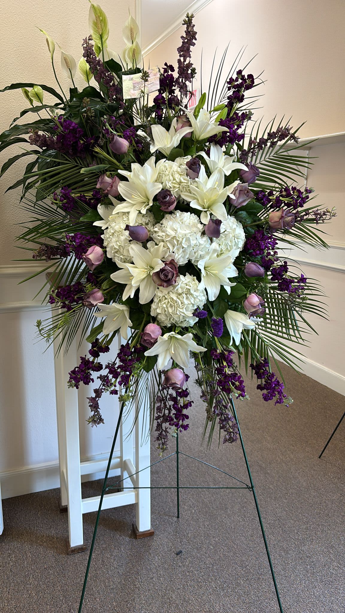 Funeral Spray Standing - The Funeral Spray Standing White is a serene and elegant tribute, combining pure white and soft purple blooms with lush greenery, offering a peaceful and respectful expression of remembrance.