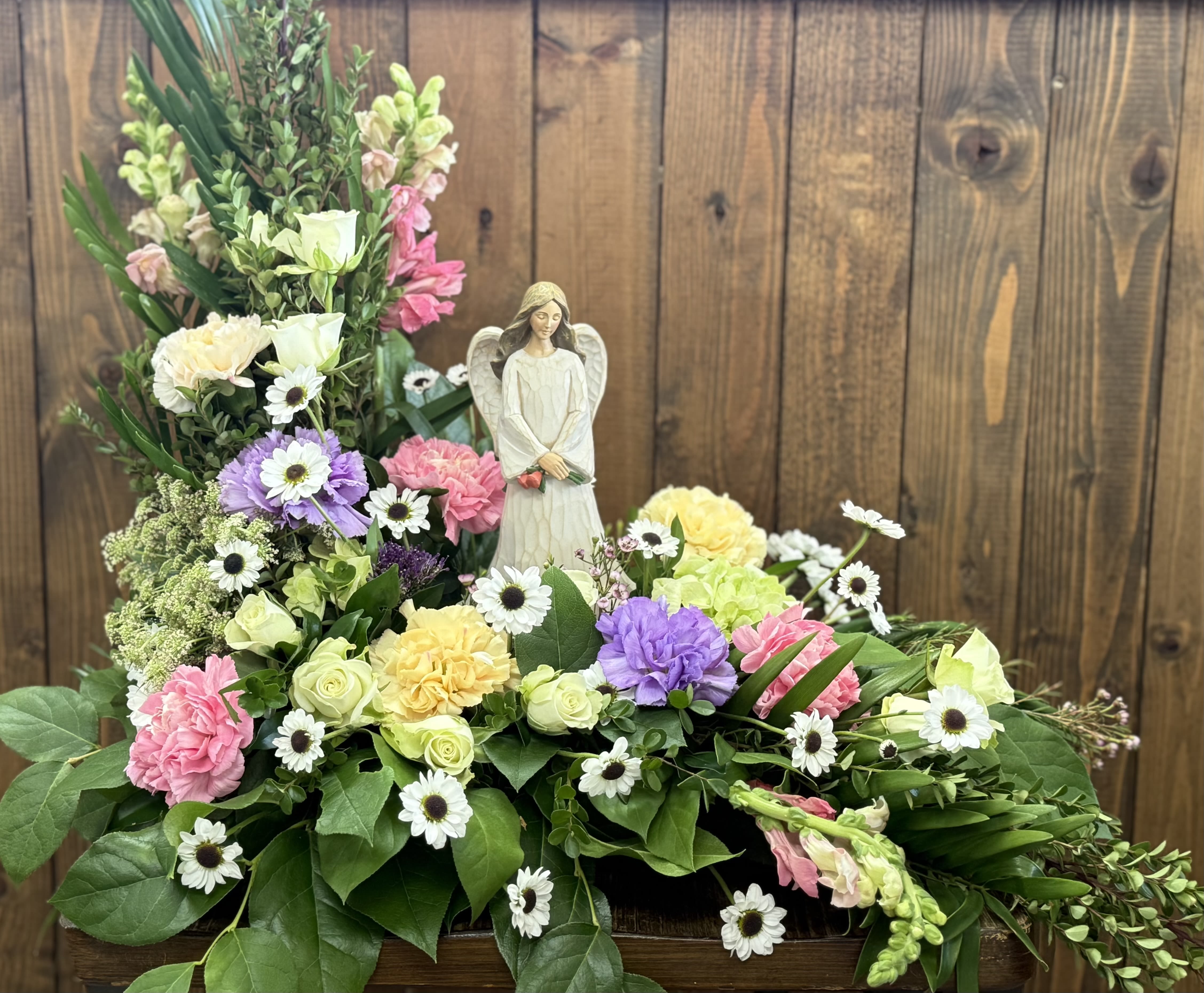 Heaven’s Embrace Heaven’s Embrace - Graceful and serene, this angel arrangement offers a heartfelt symbol of peace and eternal love. Surrounded by beautiful blooms this design radiates a sense of heavenly calm.