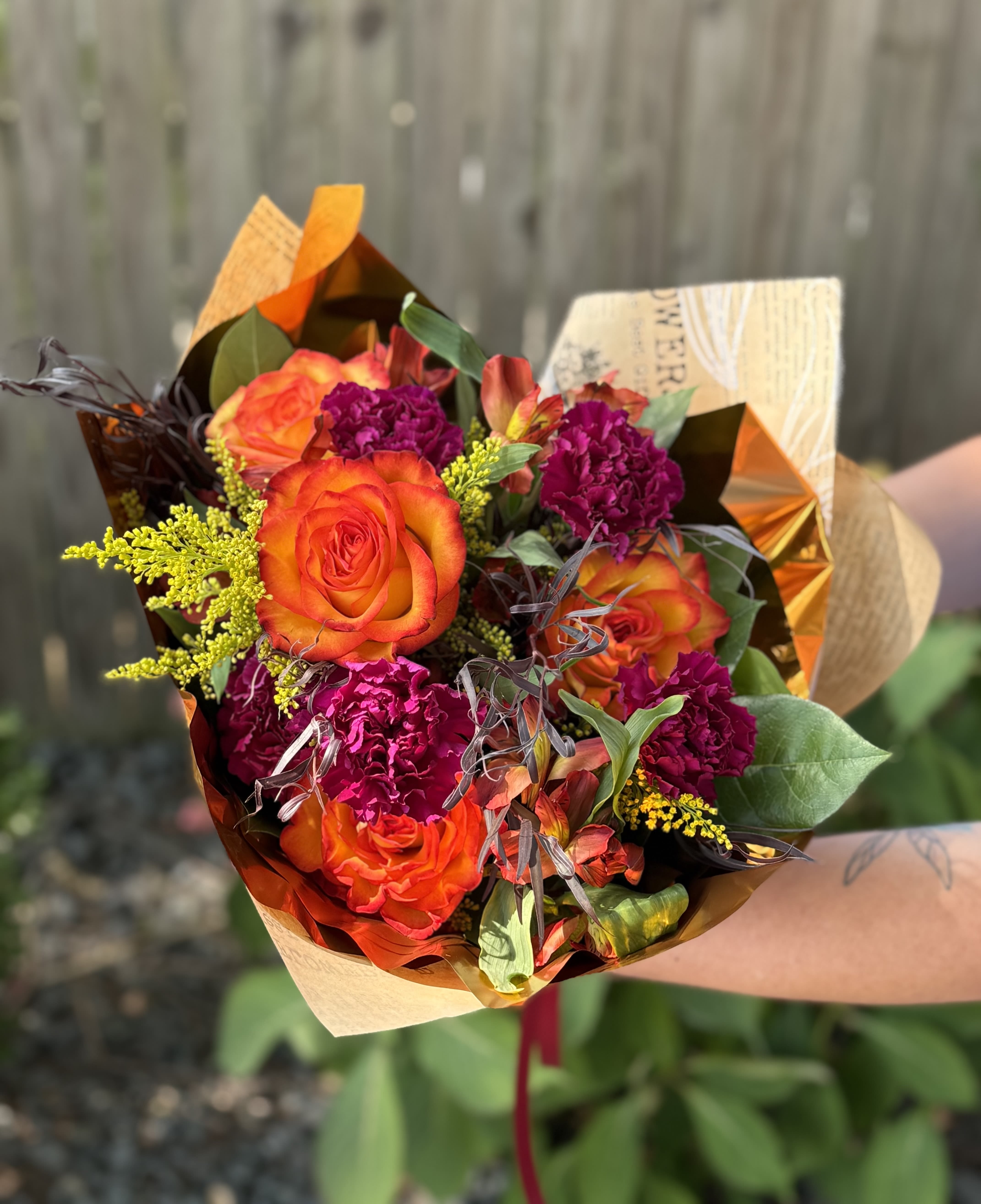 Wildfire Passion Wrap - The blazing orange of the roses like fire, the deep magenta blooms like passion. Set her heart on fire with this arrangement of flowers wrapped in our signature floral brown paper and metallic tissue paper.
