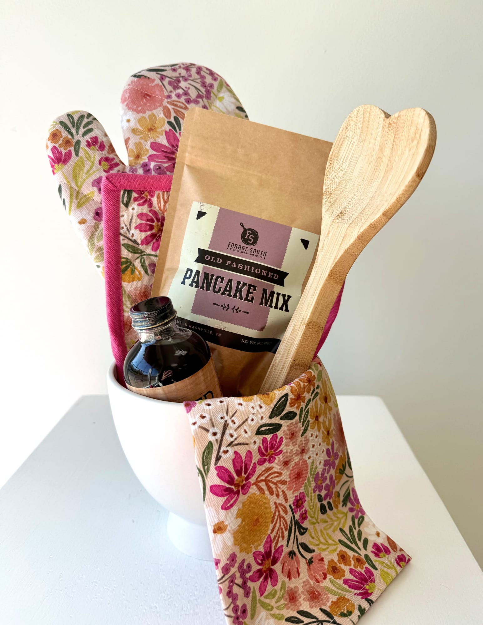 Hearts &amp; Home Bundle - Wrap your kitchen in warmth with the Hearts &amp; Home Bundle, a perfect gift for the special person in your life. This gift bundle includes a matching tea towel, oven mitt, and pot holder set, plus pancake mix, Tapped maple syrup, and a heart-shaped wooden spoon. 