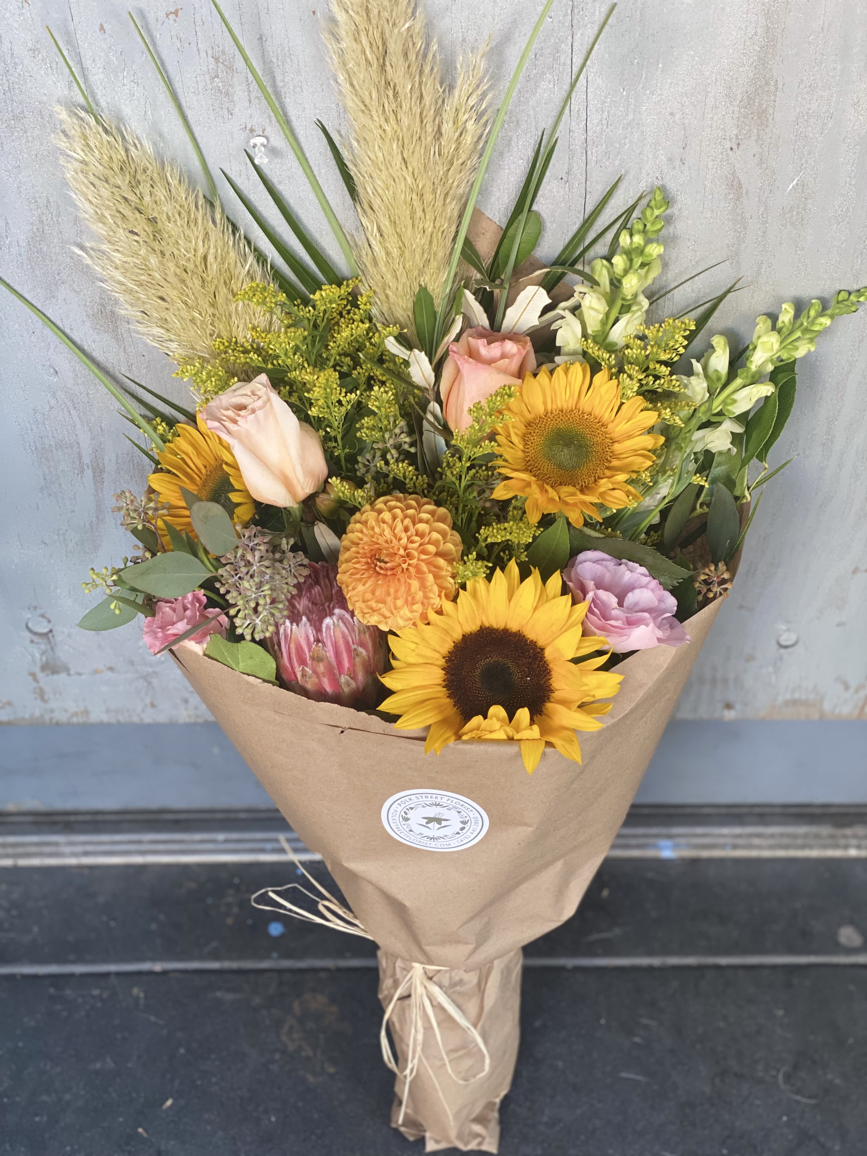 Autumn Wrap Bqt Autumn Wrap Bqt - This gorgeous wrapped bouquet comes with sunflowers, roses, and other assorted flowers in autumn shades