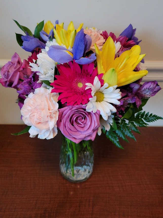 Bright and Fun - Bright beautiful mix including yellow lilies, gerbera daisies, Iris, daisies, carnations, alstromeria and roses. Arranged in a clear vase.