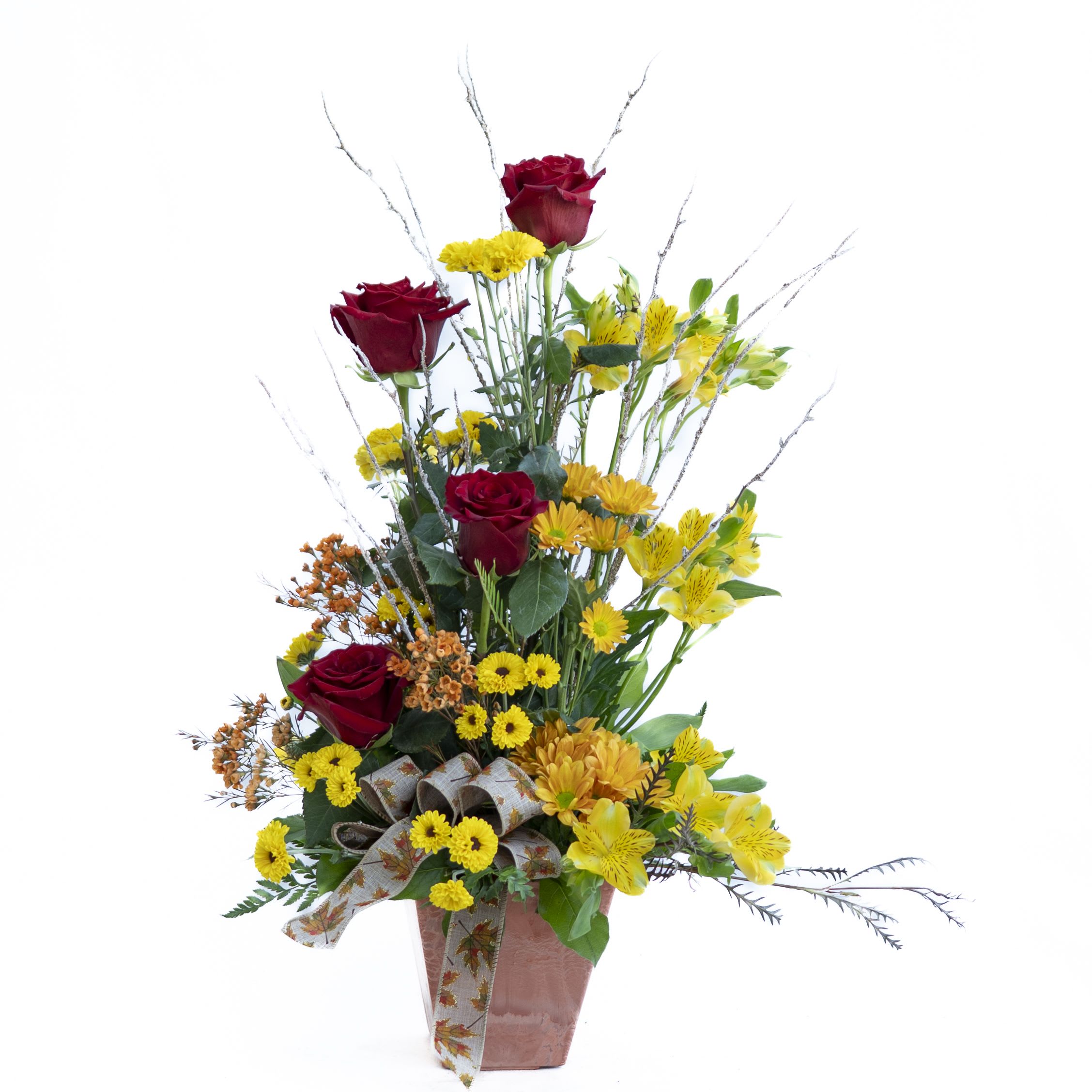 Harvest Splendor Arrangement Harvest Splendor Arrangement - Make a bold seasonal statement with our Harvest Splendor Arrangement. Designed in a tall, one-sided style, this striking display features radiant red roses, golden yellow alstroemeria, cheerful Viking and butterscotch poms, and touches of orange wax flower. A natural looking branch adds height and texture, while a festive fall bow completes the look. Presented in a rustic faux terra cotta container, it’s the perfect accent for entryways, sideboards, or any space that celebrates autumn’s beauty.