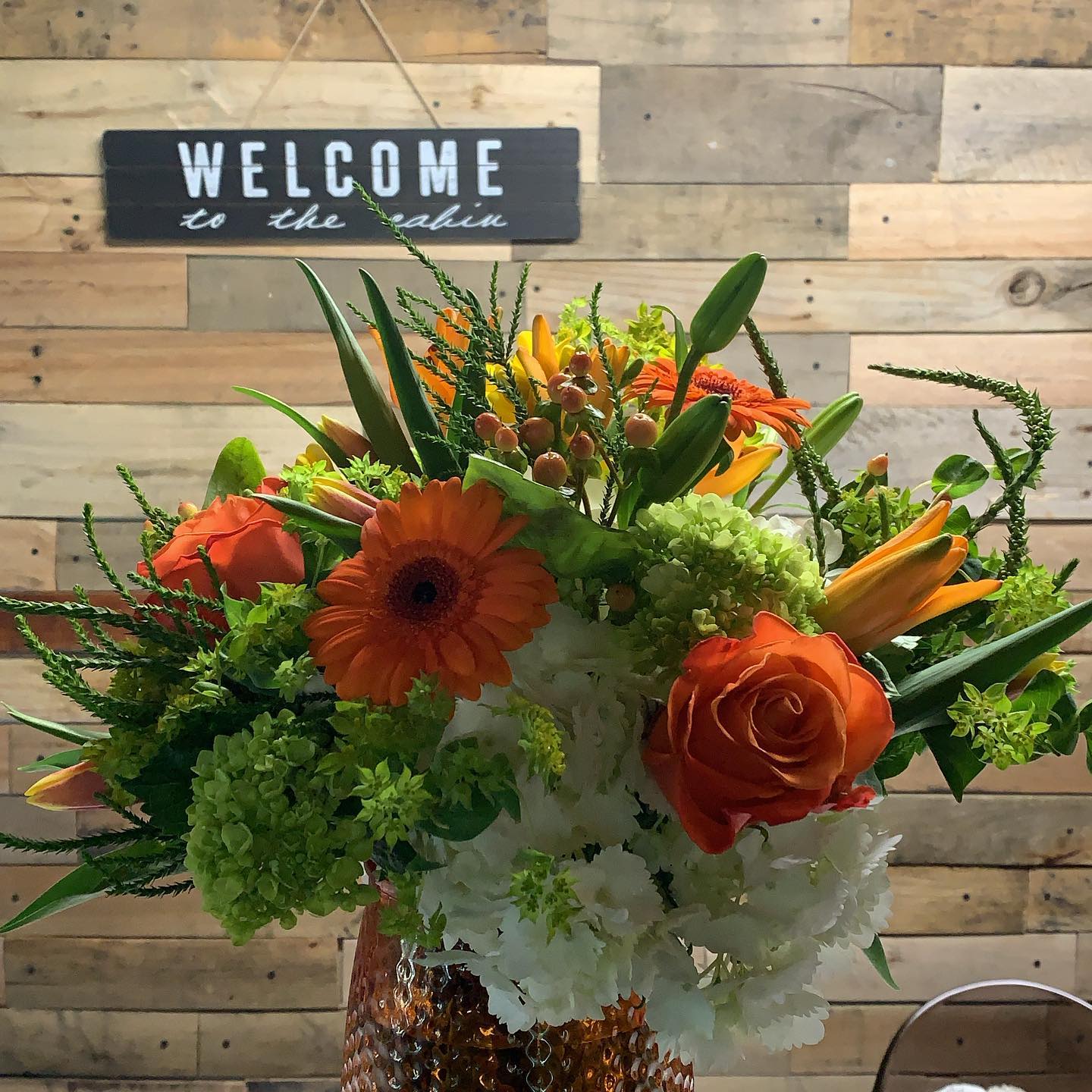 Harvest Embrace Harvest Embrace - Orange is the focal in roses, gerbera daisies and lilies beautifully arranged with green and white hydrangea accompanied by a variety of greens.