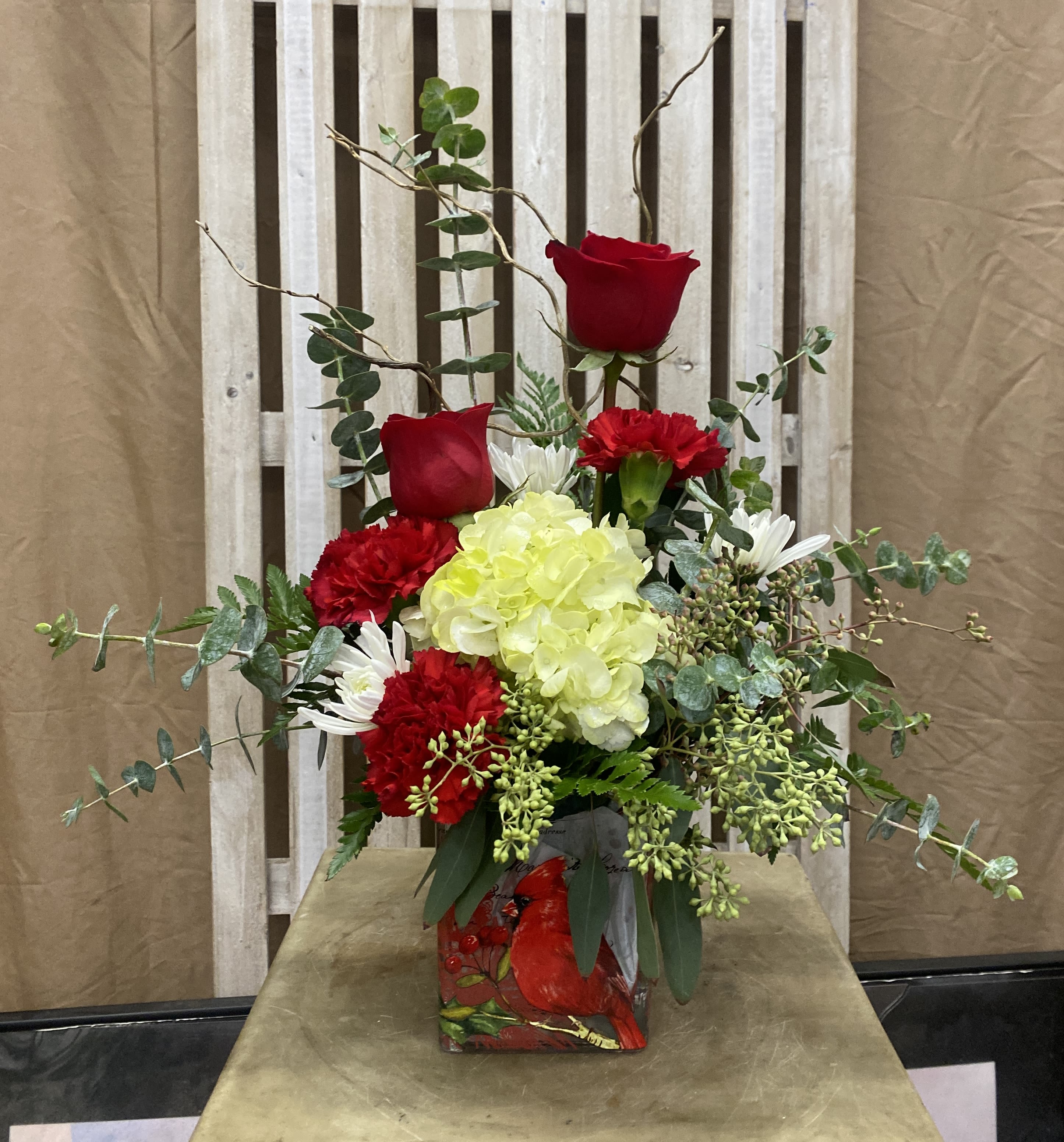 Whispers of the Woodland Heart Whispers of the Woodland Heart - A charming blend of nature and love, Whispers of the Woodland Heart features soft blooms and lush greenery arranged in a cardinal-adorned vase. Designed in a graceful one-sided style, its woodsy elegance and gentle tones evoke the warmth of lasting affection and the quiet beauty of the forest year-round.