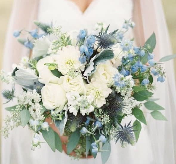 Dusty Blue By D Bryant Designer - This subtle design will set the tone for an elegant affair. Designed with blue delphinium, roses and hydrangeas and mixed foilages. We can create this as a bridal bouquet or as a centerpiece for a classic special occasion.