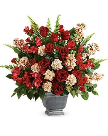 Teleflora's Bold Tribute Bouquet - A bold expression of your deepest condolences, this elegant mix of red blooms in a large antiqued pot brings strength and comfort. Red roses, red alstroemeria, red carnations, miniature red carnations, and burgundy stock are arranged with spiral eucalyptus, seeded eucalyptus, sword fern, and lemon leaf. Delivered in a Modern Heritage pot.