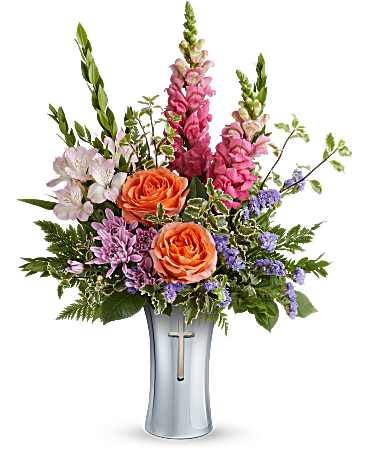 Teleflora's Glory's Embrace Bouquet - Honor faith and love with the Glory's Embrace Bouquet, a radiant mix of graceful blooms presented in the Shining Cross Vase. With its silver finish and elegant cross cutout, this timeless keepsake offers a heartfelt tribute of comfort, peace, and remembrance. The Glory's Embrace Bouquet features orange roses, pink alstroemeria, pink snapdragons, lavender cushion spray chrysanthemums, purple sinuata statice, leatherleaf fern, myrtle, and pitta negra. Arranged in the Shining Cross Vase, this elegant bouquet offers a heartfelt expression of comfort and peace.