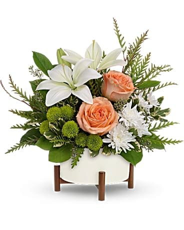 Teleflora's Mod Blooms Bouquet - As unique as they are! This delightfully different arrangement features peach roses and snow white lilies in a retro-inspired ceramic and wood planter. Peach roses, white asiatic lilies, green button spray chrysanthemums and white button spray chrysanthemums are arranged with grevillea, variegated pittosporum, lemon leaf and seeded eucalyptus. Delivered in a Mid-Century planter.
