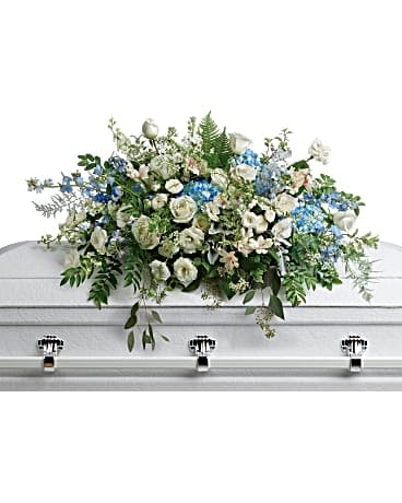 Tender Remembrance Casket Spray - As soft and delicate as a tender remembrance, this stunning spray of sky blue hydrangea and pure white roses brings a fresh, natural beauty to the casket. This stunning spray includes blue hydrangea, white roses, white spray roses, white alstroemeria, white lisianthus, blue delphinium, white larkspur, white stock, white waxflower, dusty miller, huckleberry, asparagus plumosus, pitta negra, lily grass, dagger fern, and lemon leaf.