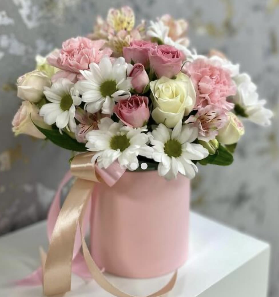 Pure Grace Flowers in a Box Pure Grace Flowers in a Box - The “Pure Grace” is an elegant arrangement featuring pristine white chrysanthemums and classic roses. Presented in a chic hatbox, this bouquet combines the lush fullness of chrysanthemums with the timeless beauty of roses, creating a sophisticated and serene display. Perfect for any special occasion or as a thoughtful gift, this arrangement brings a touch of grace and purity to any setting.