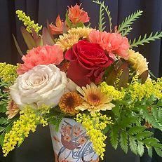 Harvest Blooms Harvest Blooms - “Harvest Blooms” Celebrate the beauty of the season with this charming fall arrangement featuring lush red and cream roses, coral carnations, and golden mums surrounded by fresh greenery and sprigs of solidago. Artfully arranged in a decorative autumn container, this design brings warmth and rustic elegance to any space — perfect for a cozy home accent or thoughtful gift.