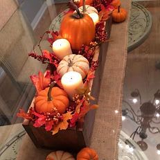 Pumpkin Harvest Centerpiece Pumpkin Harvest Centerpiece - Bring the warmth of autumn to your table with our Pumpkin Harvest Centerpiece. Nestled in a rustic wooden box, this charming arrangement features a mix of mini pumpkins, soft ivory candles, vibrant fall leaves, and seasonal berries. Perfect for a Thanksgiving table, entryway, or cozy fall gathering, it adds a welcoming glow and festive touch to any space.