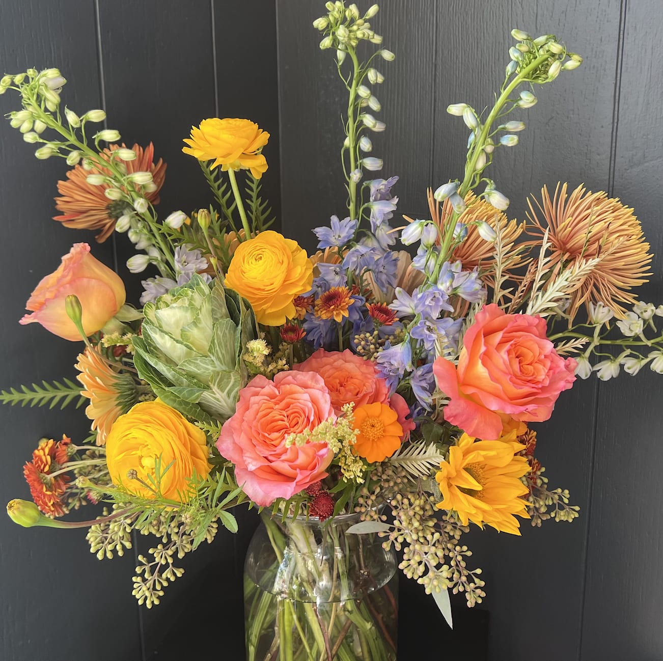 EXTRA LARGE SEASONAL ARRANGEMENT IN GLASS VASE, DESIGNER'S CHOICE - Seasonal, colorful flowers and foliage artfully arranged in a clear glass vase.  Year round flowers that we typically stock: specialty rose, spray rose and garden rose, ranunculus, anemone, gerbera daisy, protea, lisianthus, chrysanthemum, larkspur, snapdragon, delphinium, stock, aster, dianthus, hypericum, feverfew, astrantia, leucodendron.
