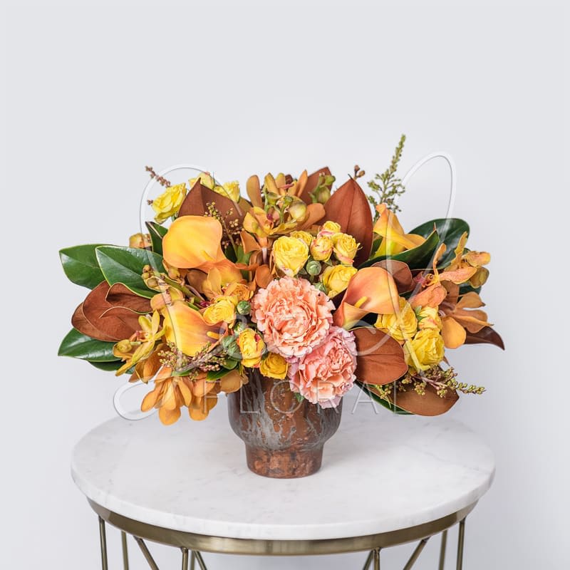 Falling for You - Our Falling for You arrangement captures the warmth and romance of autumn. Featuring rich Magnolia, Garden Roses, Mokara Orchids, Calla Lilies, Spray Roses, and Pieris, artfully arranged in a chic Copper Pot. Perfect for adding a cozy, seasonal touch to your dining or coffee table.
