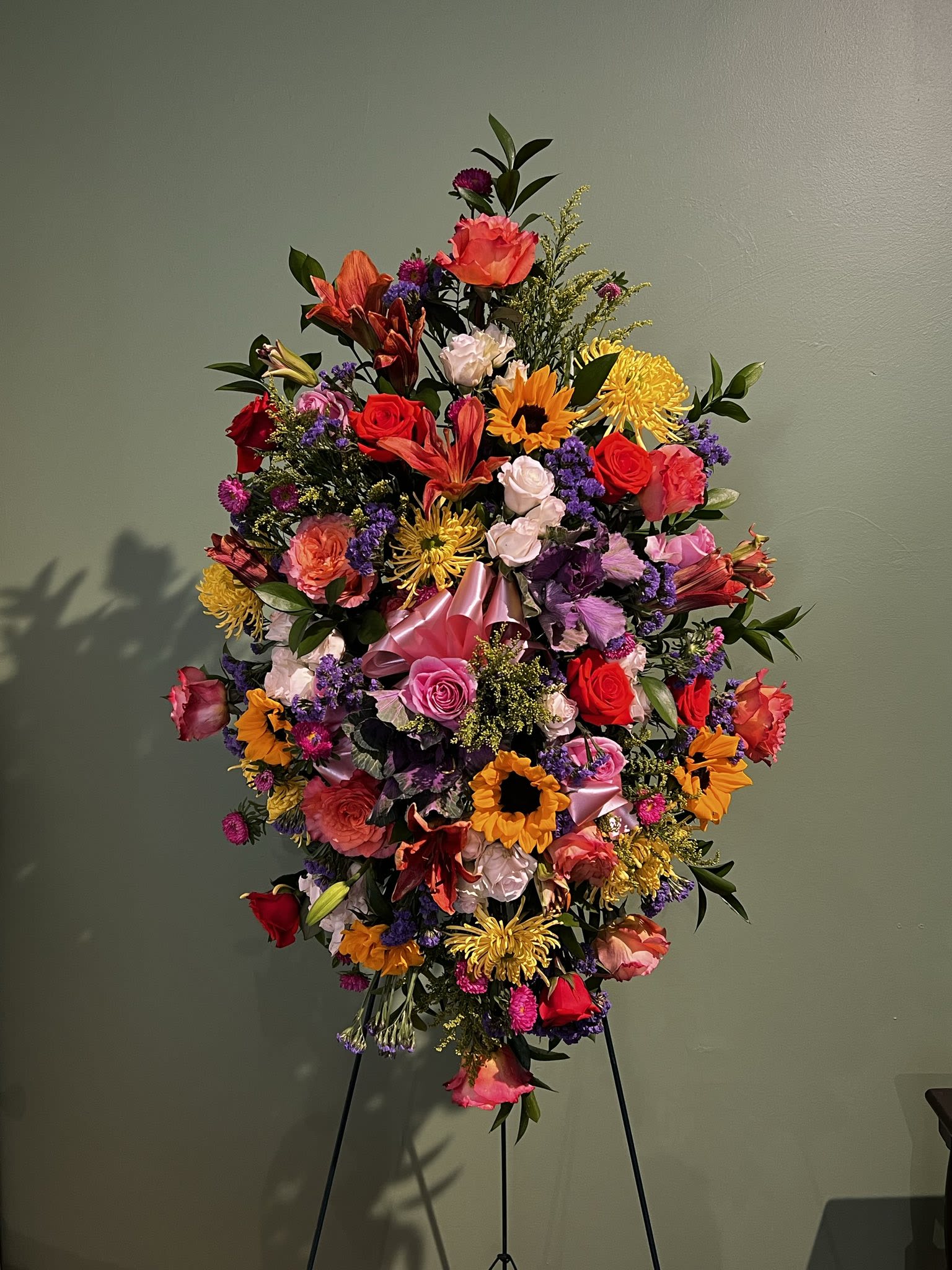 Multi Color Sympathy Spray - Send a multicolored floral bouquet to show your sympathy and support. Created with fresh flowers in red, yellow, pink and orange colors and arranged on a spray easel. Usually sent to a family, friend or business associate.