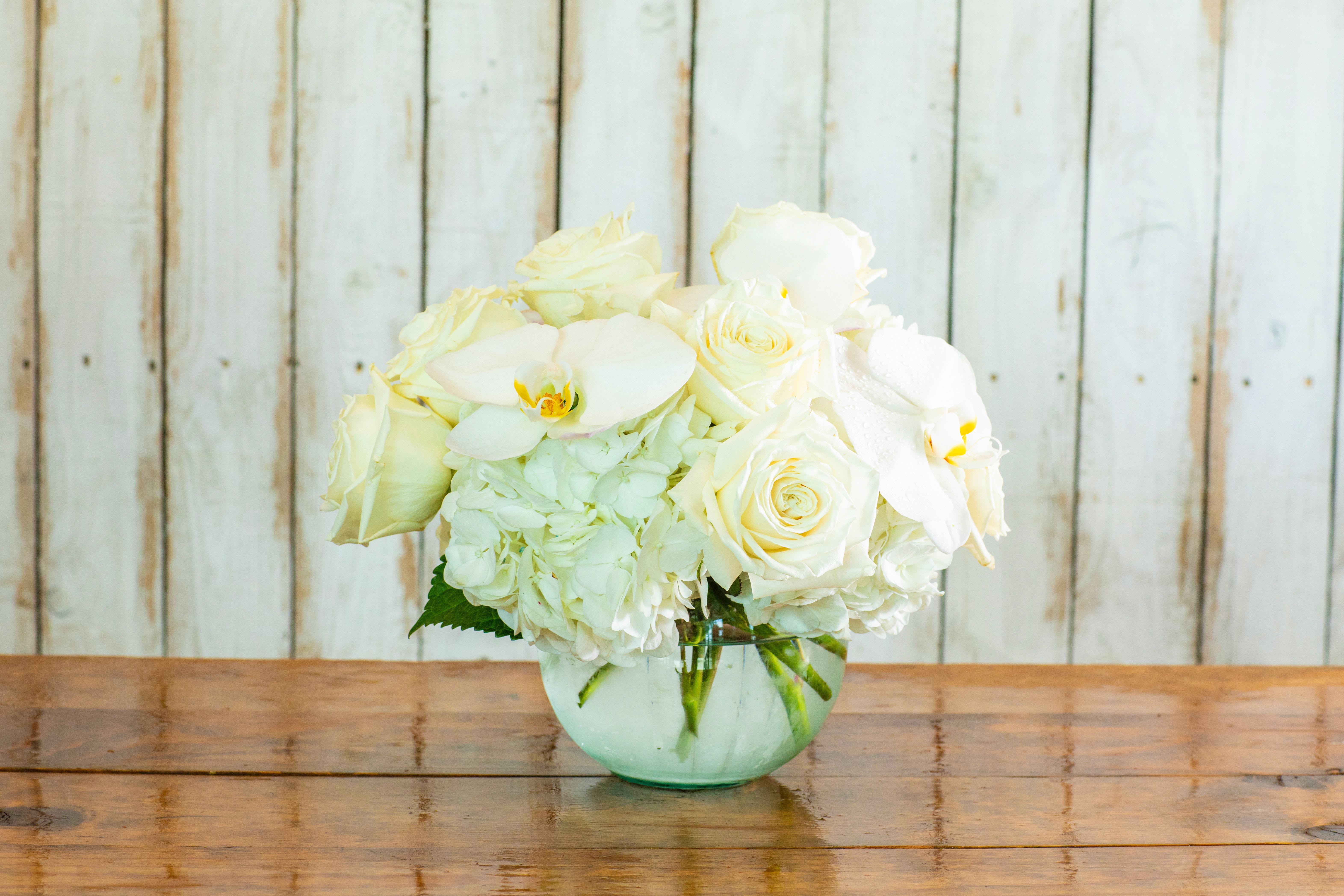 Elegant White Cloud Bouquet - Experience pure serenity with the Elegant White Cloud Bouquet, a sophisticated and pristine arrangement crafted by your distinguished Rancho Cucamonga Florist. This exquisite bouquet exudes grace and tranquility, featuring a luxurious blend of fresh white blooms.  It showcases plush white hydrangeas as its cloud-like base, perfectly complemented by classic creamy white roses and delicate white phalaenopsis orchids. The varying textures and shades of white create a rich, ethereal display. This gorgeous composition is beautifully arranged in a stylish, clear rounded glass vase, enhancing its classic appeal.  As the leading Rancho Cucamonga flower shop, we are committed to providing the most elegant and high-quality floral designs. The Elegant White Cloud Bouquet is an ideal choice for conveying heartfelt sentiments, perfect for sympathy flowers, a refined anniversary gift, a chic birthday bouquet, or as an elegant accent for a home or office. It also makes for a beautiful bridal shower gift.  We offer reliable same-day flower delivery throughout the entire Rancho Cucamonga area, ensuring your pristine flowers arrive in perfect condition. Trust our expertise for beautiful and thoughtful floral gifts. Order the Elegant White Cloud Bouquet online today from your trusted local Rancho Cucamonga Florist!