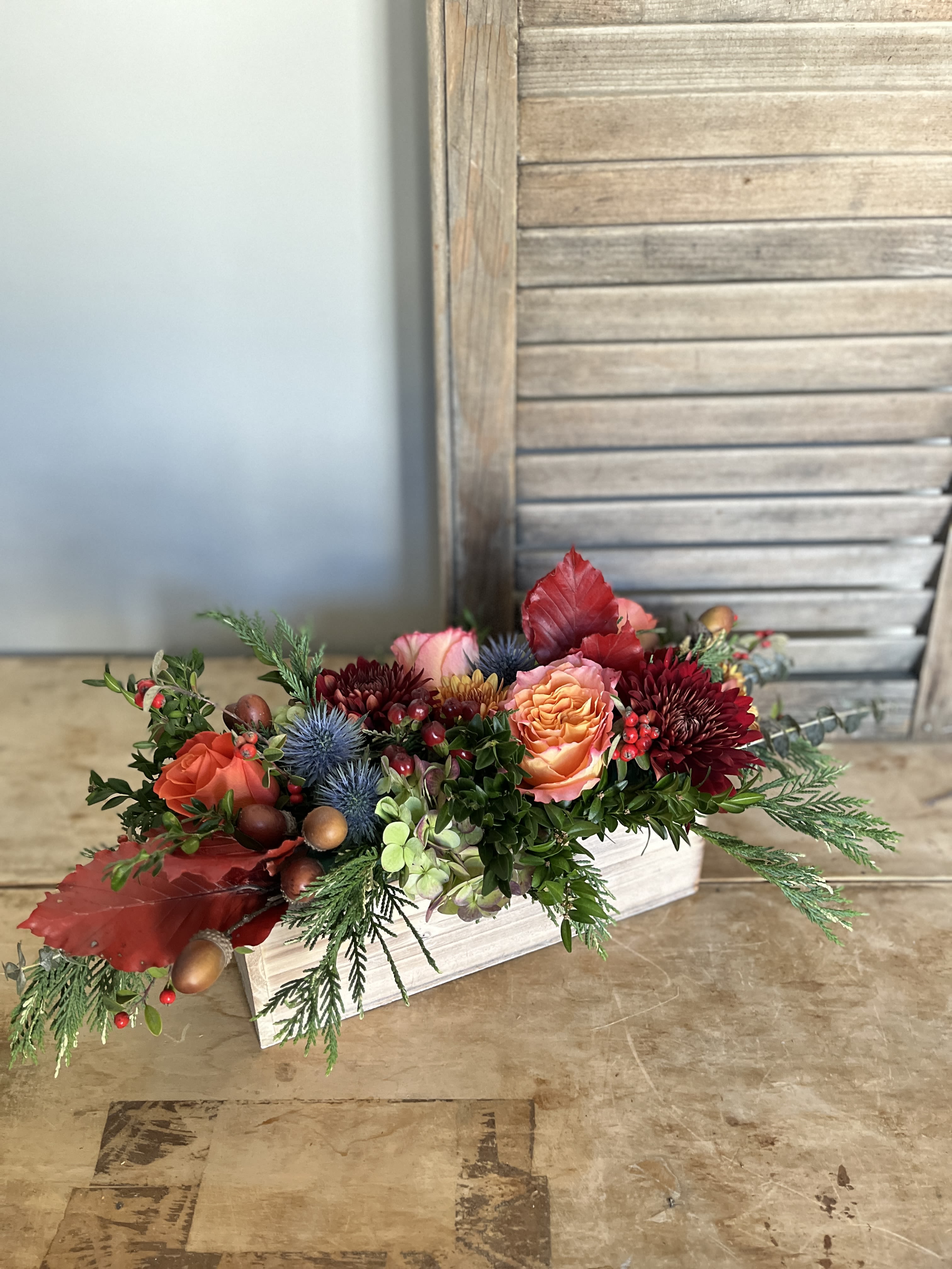 Harvest Centerpiece  - A bountiful holiday centerpiece to grace your table. Designed in a rustic wooden box, this abundant arrangement uses hues of rust, gold and cranberry to evoke the flavor of the season. Candles are optional and additional. Approx 20&quot; long. 