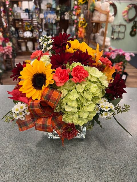 Harvest Blooms (HBS) Harvest Blooms (HBS) - Our Contemporary Autumn design in a clear square vase filled with green hydrangea, sunflowers, roses and more. It is bright and cheerful for the season. *Each of our designs are unique, therefore flowers and colors may differ, however they will be just as beautiful