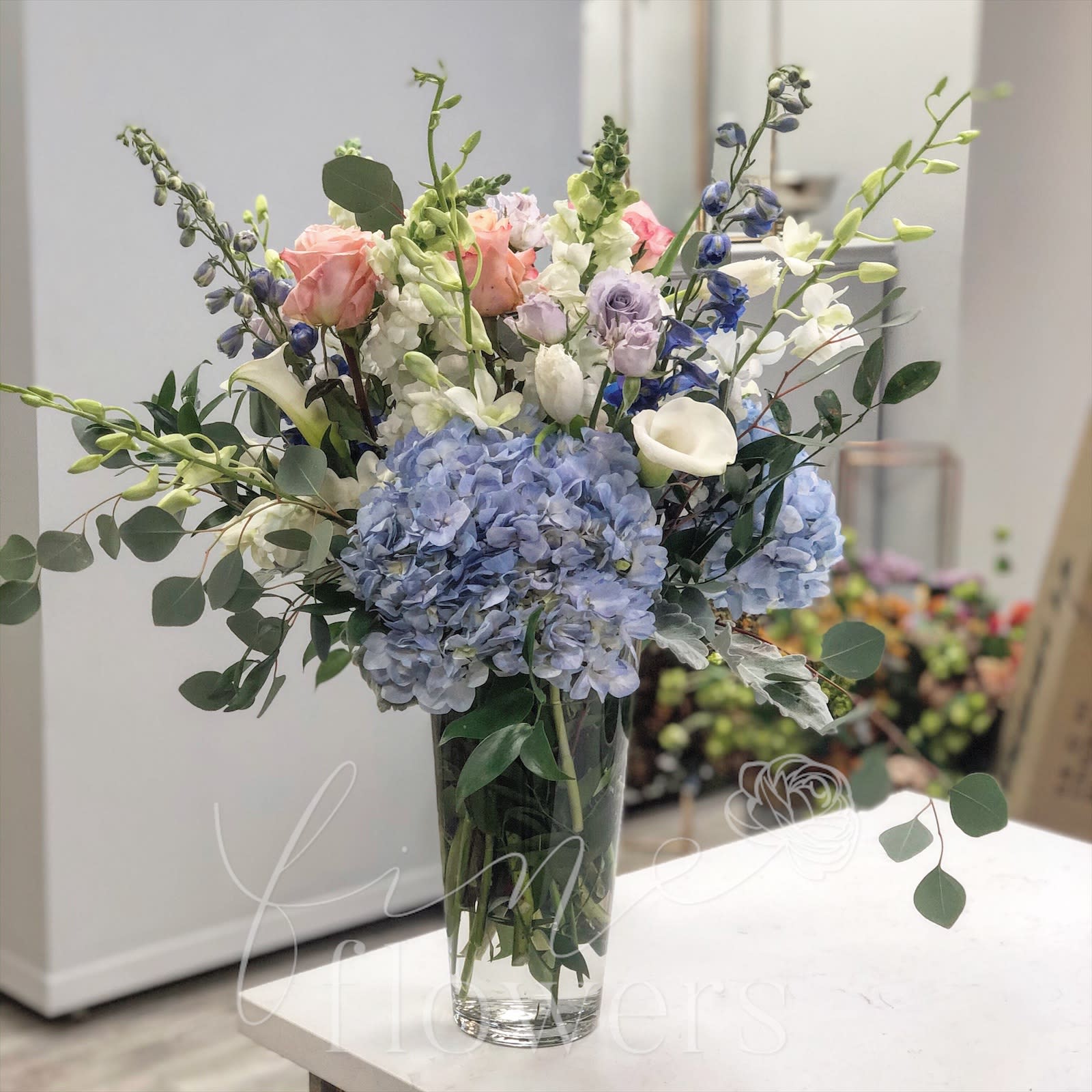 St. Jean St. Jean - St. Jean is an incredible display of blues, lavenders, peach and white comprised of all upscale and elegant flowers. St. Jean includes Calla Lilies, Hydrangea, Freesia, Roses, Spray Roses, Stock, Snapdragons and more in our extra large sized Riviera glass vase.