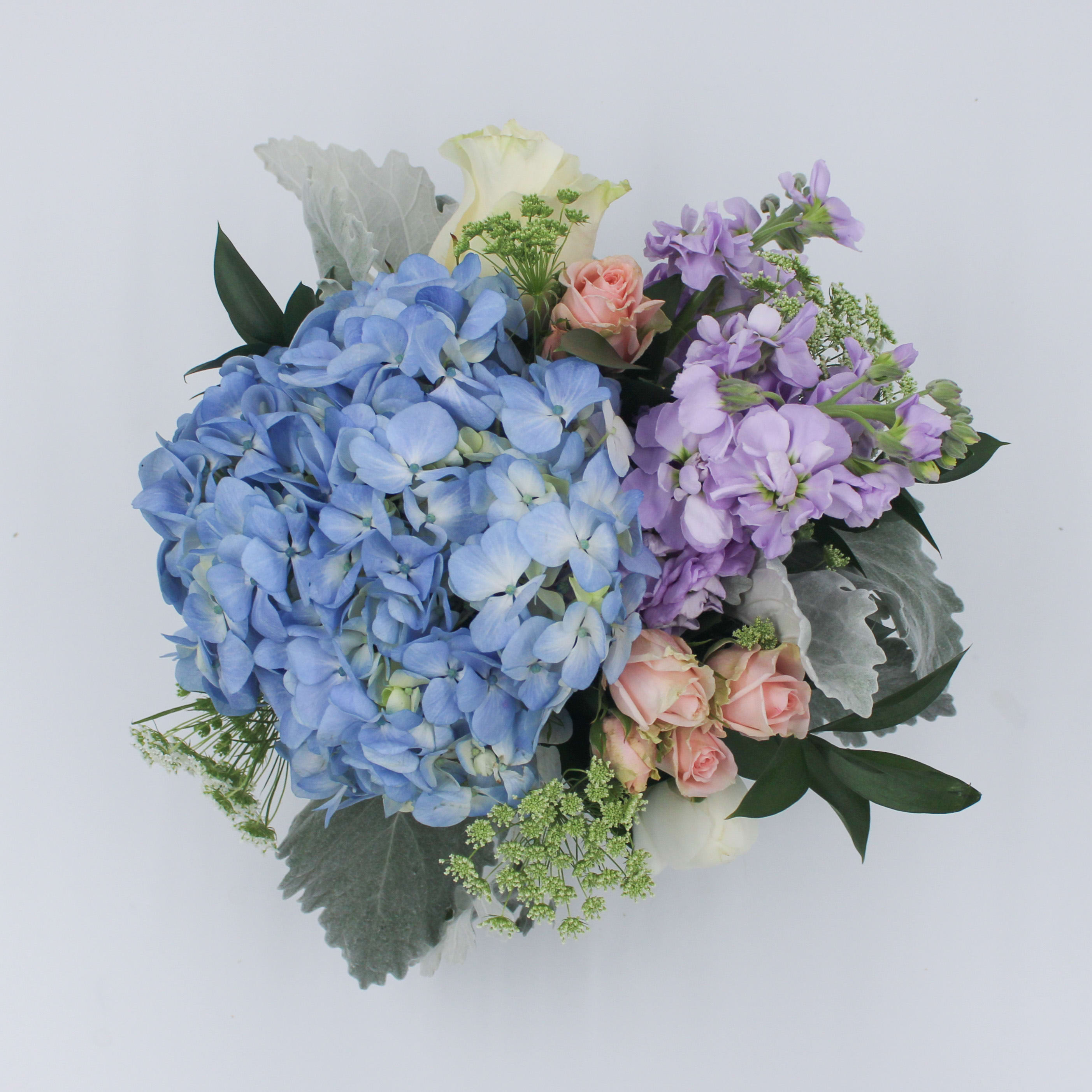 Sea Glass - Sea Glass is a pastel beauty that features a Blue Hydrangea, Lavender Stock, White Rose, Blush Spray Rose, White Ranunculus, Dusty Miller, Queen Anne's Lace, and Israeli Ruscus arranged in a 6-inch clear glass bubble bowl.  The Premium Sea Glass is arranged in an 8 in. glass bubble bowl.