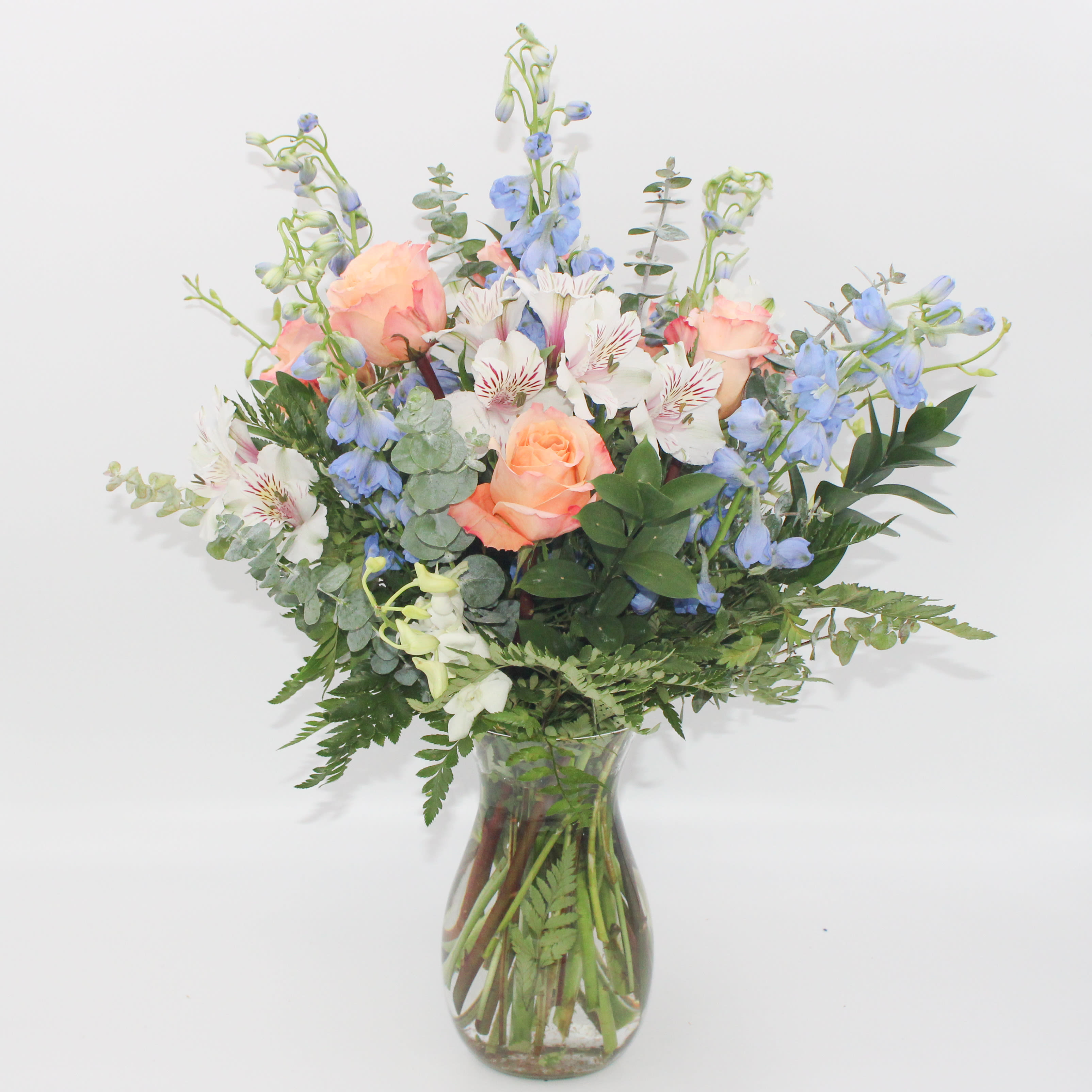 Sea Breeze Sea Breeze - Sea Breeze is a refreshing mix of blues, whites and peach perfect for spring or summer. Sea Breeze includes White Dendrobium Orchid Stems, White Alstroemeria, Peach Roses, Blue Delphinium, Baker Fern and Spiral Eucalyptus.