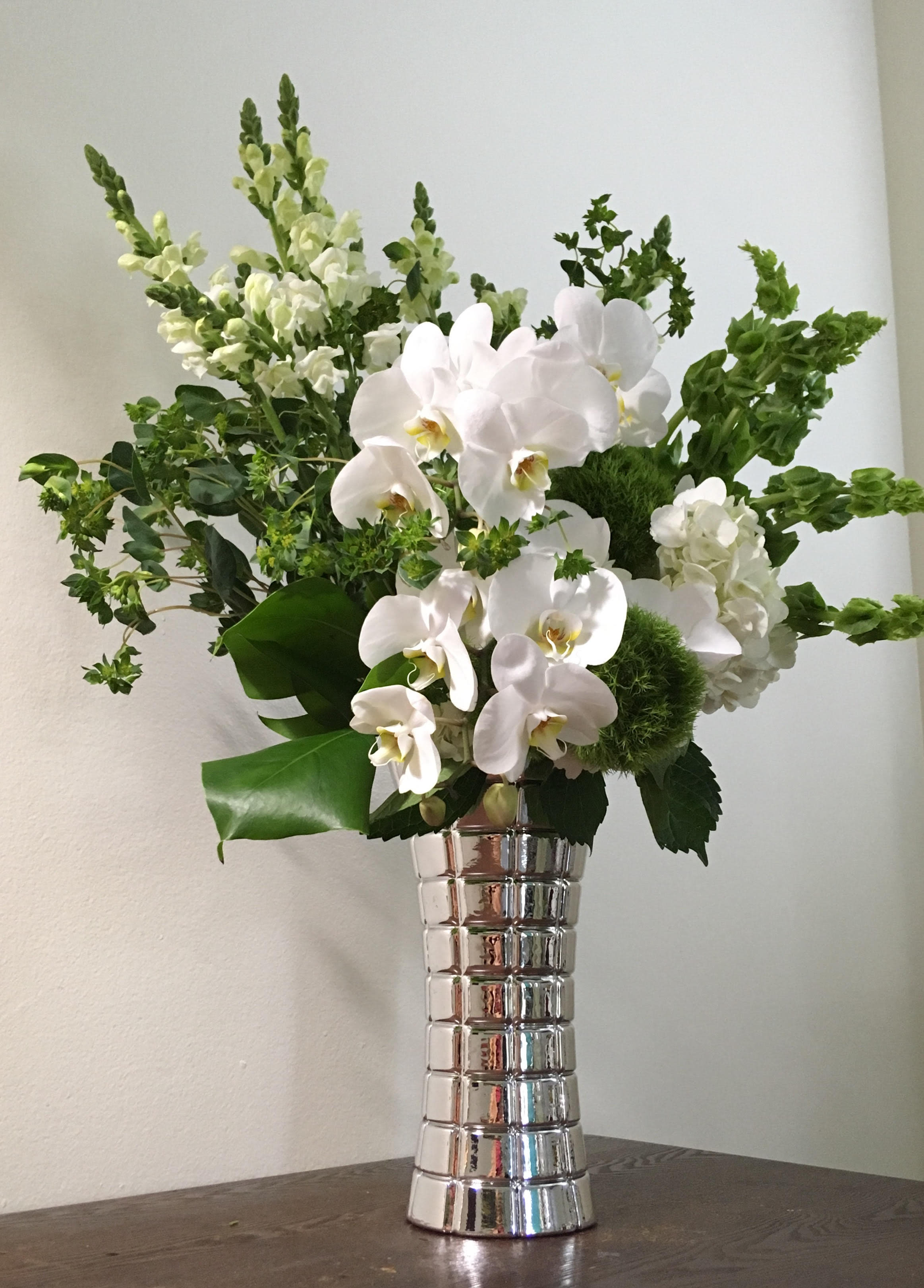 Emerald Pearls - White Phalaenopsis Orchid blooms , White Hydrangeas, Bells of Ireland ,green in tall glass silver fancy vase 