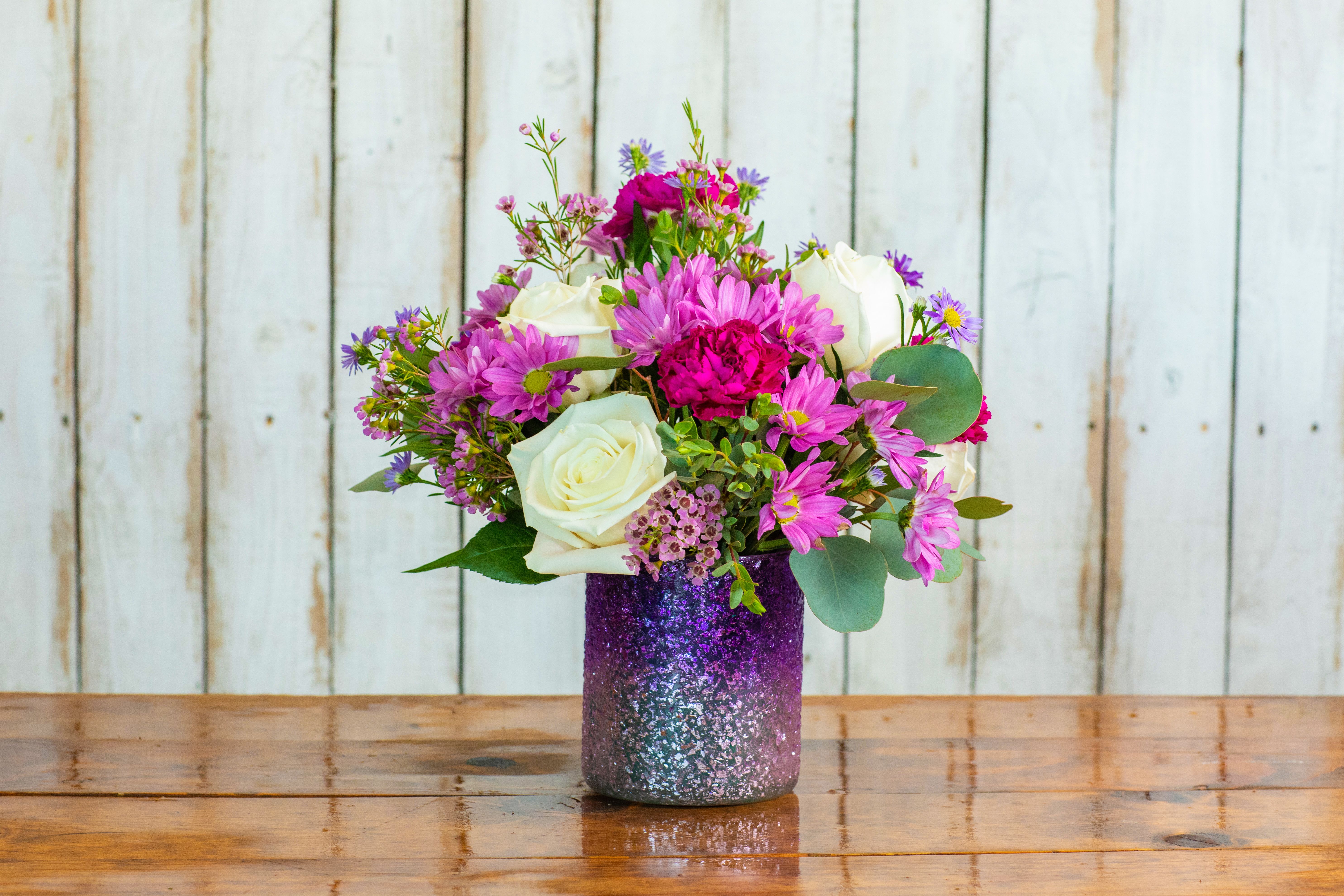 Twilight Sparkle Bouquet Twilight Sparkle Bouquet - Introducing the Twilight Sparkle Bouquet, a dazzling creation from your trusted Rancho Cucamonga Florist, Tommy Austin Florist. This enchanting arrangement captures the soft, shimmering colors of a fading sunset. It features creamy white roses symbolizing purity and new beginnings, beautifully contrasted with vibrant blooms like fuchsia and lavender chrysanthemums and delicate pink daisies. The entire mix is elegantly accented with small filler flowers and a touch of silvery eucalyptus. But the true showstopper is the presentation: a stunning, glitter-dipped vase that transitions from silver to deep purple, making this a truly unique and memorable gift. Perfect for celebrating a new baby, a friendship, or adding a glamorous touch to any space. Order the "Twilight Sparkle" today for local hand-delivery across Rancho Cucamonga!