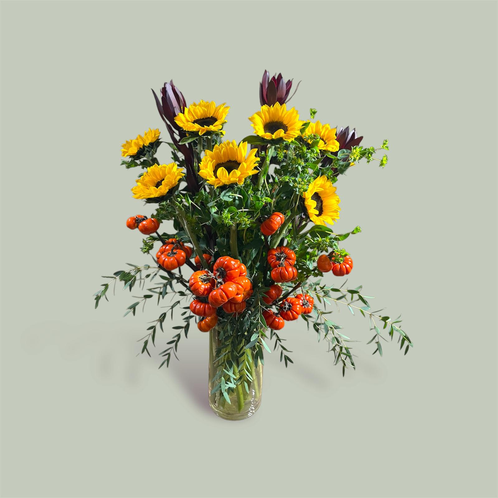 For the Fall - This beautiful arrangement is made up of sunflowers, spray pumpkins, bupleurum, safari sunset, and eucalyptus gunni in a tall glass vase.