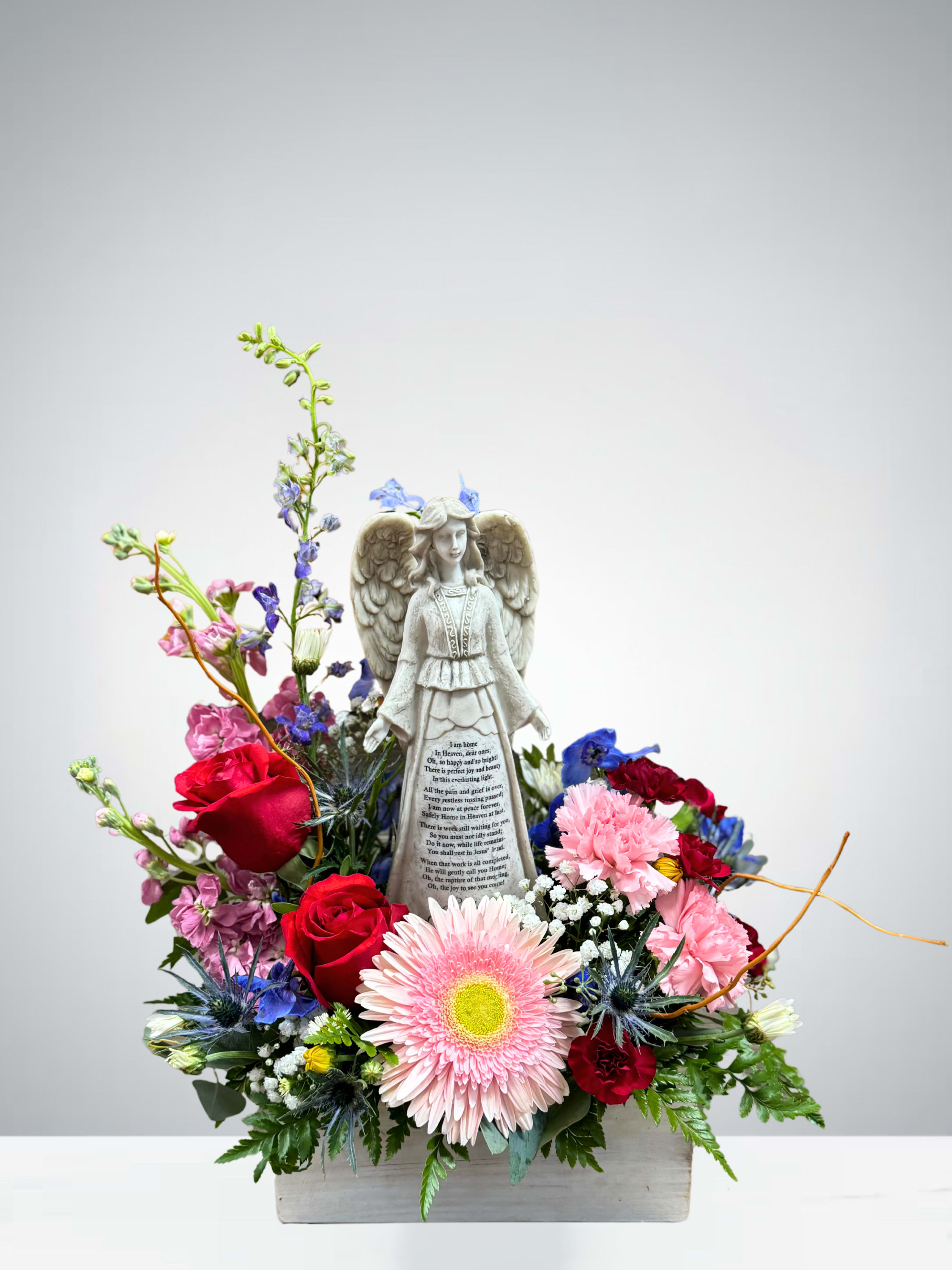 Angel’s Touch - This peaceful arrangement features a graceful angel surrounded by a mix of soft, comforting blooms. With roses, mini carnations, gerbera daisy, and accent flowers in gentle colors, it’s a heartfelt way to share love and remembrance. The angel figurine adds a special touch, offering a sense of comfort and hope.  (Flower colors and varieties may vary based on availability.)