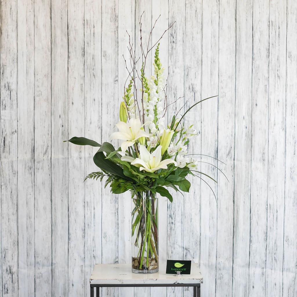 Canvas Canvas - Simply stylish and classy a vase of elegant white blooms is accented with natural stones and branches. Approximate Dimensions: 30" H x 16" W