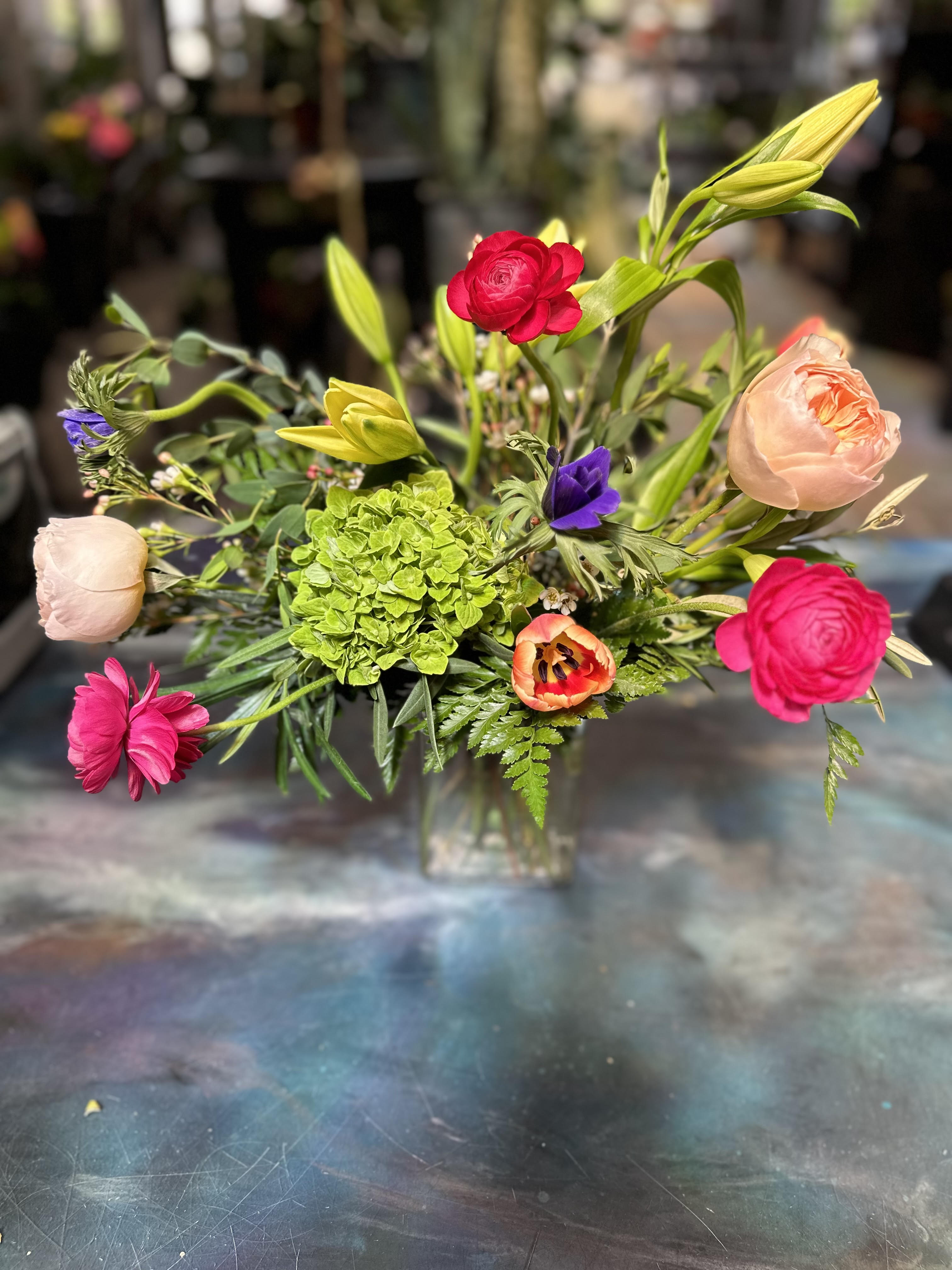 Summer Sorbet  - Designed using peach Juliet garden roses, yellow asiatic liles, hot pink raspberry ranunculus, cool blue anemones, and green hydrangeas, with lush, textural foliage. 
