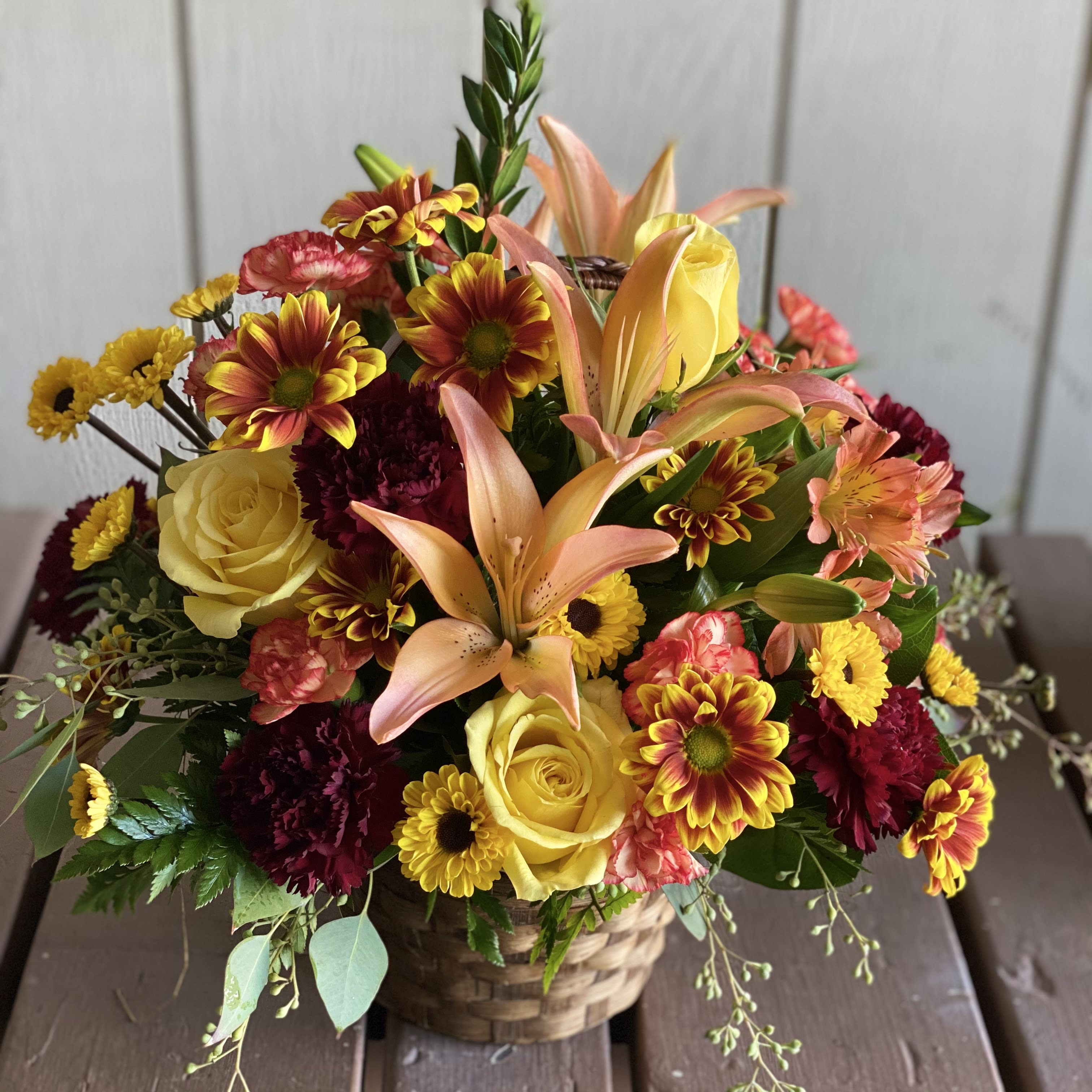 Fall Basket Fall Basket - Seasonal fall flowers arranged in a stained basket.