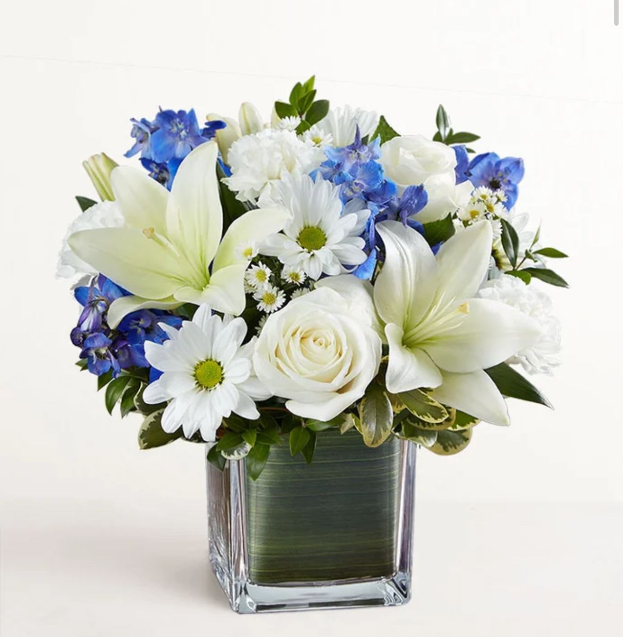 Healing Tears Healing Tears - Soothe their tears as they mourn the loss of a loved one with the serenity of blue and white. Our sympathy arrangement of fresh blue delphinium, white roses and lilies, expertly gathered together in a clear glass cube lined with Ti leaf ribbon, makes for an exquisite gesture of comfort and healing.