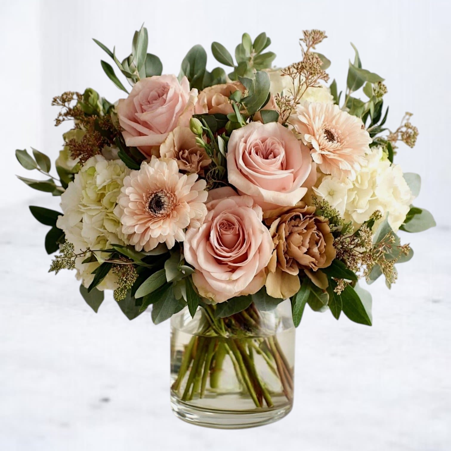 Mocha Petal Elegance Mocha Petal Elegance - Soft romance meets timeless beauty in our Mocha Petal Elegance Bouquet, a refined arrangement featuring creamy hydrangea, blush roses, beige lisianthus, and delicate gerbera blooms. The mocha-toned lisianthus adds unexpected depth, perfectly complementing the gentle pastel palette and lush greenery. Designed in a clear glass vase, this bouquet exudes a modern yet classic charm — making it an ideal gift for birthdays, anniversaries, or as an elegant sympathy gesture. Available for same-day flower delivery in Houston, Magnolia, The Woodlands, Spring, and surrounding areas, this graceful design is perfect for sending love, comfort, or congratulations.