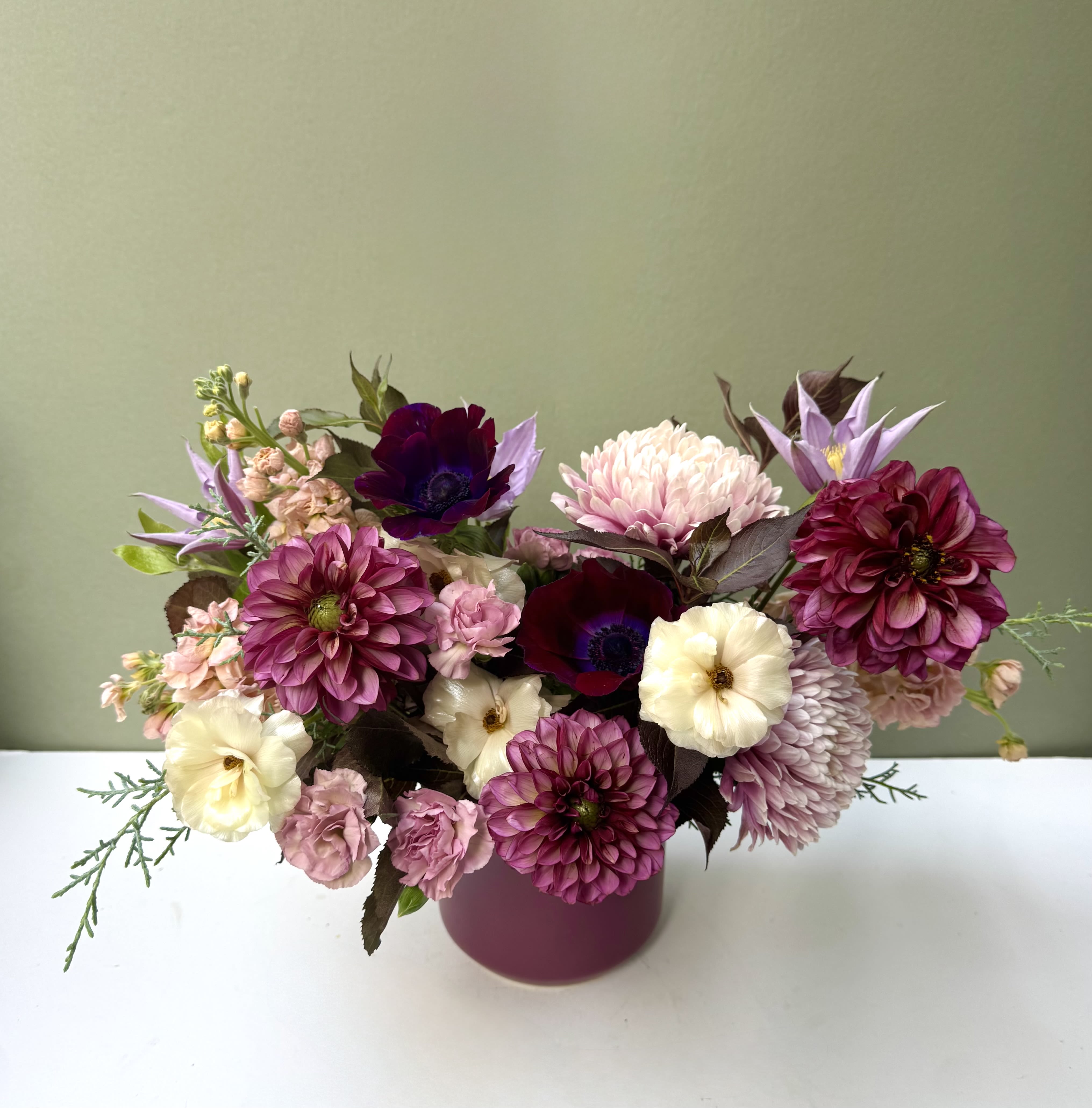 Mulberry harvest  - A lush fall arrangement brimming with dahlias, anemones, and soft garden blooms in rich plum, mauve, and cream tones. Designed in a berry-hued vase, this piece captures the warmth and elegance of autumn — romantic, modern, and full of cozy depth.