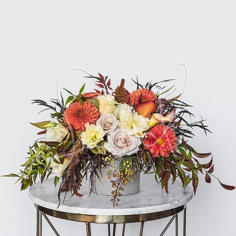 Holiday Harvest - Celebrate the season in style with Holiday Harvest, a stunning mix of vibrant dahlias, creamy roses, and burnt orange calla lilies accented by rich foliage and golden berries. Designed in a modern vessel, this arrangement embodies autumn abundance and holiday warmth, perfect for your Thanksgiving table, festive gatherings, or as a sophisticated seasonal gift.