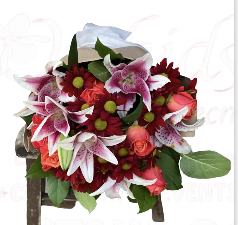 Orange Rose &amp; Stargazer Autumn Wrapped Bouquet  - Bring the warm and inviting spirit of autumn into any home or special occasion with this charming bouquet. Featuring a delightful arrangement of short-stemmed, vibrant orange roses, elegant stargazer lilies, and cheerful crimson daisies, this creation is designed to instantly brighten any fall day. Carefully wrapped in brown gift paper and adorned with a ribbon, this thoughtful gift is perfect for a friend who cherishes the season, your appreciative Thanksgiving host, or anyone you want to celebrate, no matter the occasion.