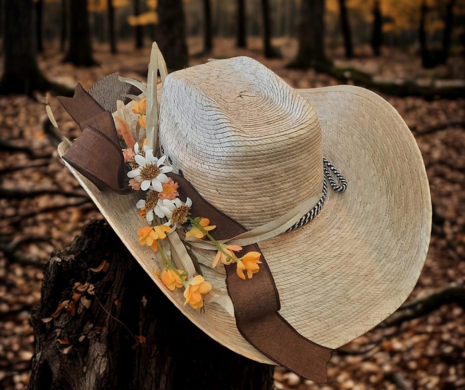SALE Southern Bloom Cowboy Hat SALE Southern Bloom Cowboy Hat - Step into the charm of the South with our Southern Bloom Cowboy Hat, a perfect blend of rustic elegance and floral beauty. Inspired by the vibrant spirit of Nashville, this straw cowboy hat is adorned with silk yellow and white flowers, capturing the essence of sunny fields and open skies. The addition of a sophisticated brown accent ribbon ties the look together, making it a standout accessory for any occasion, from country music festivals to casual outings. Whether you're looking to make a fashion statement or simply want to add a touch of "Music City" flair to your wardrobe, this hat is your go-to choice. Its lightweight design ensures comfort while its floral accents offer a fresh take on a classic style.