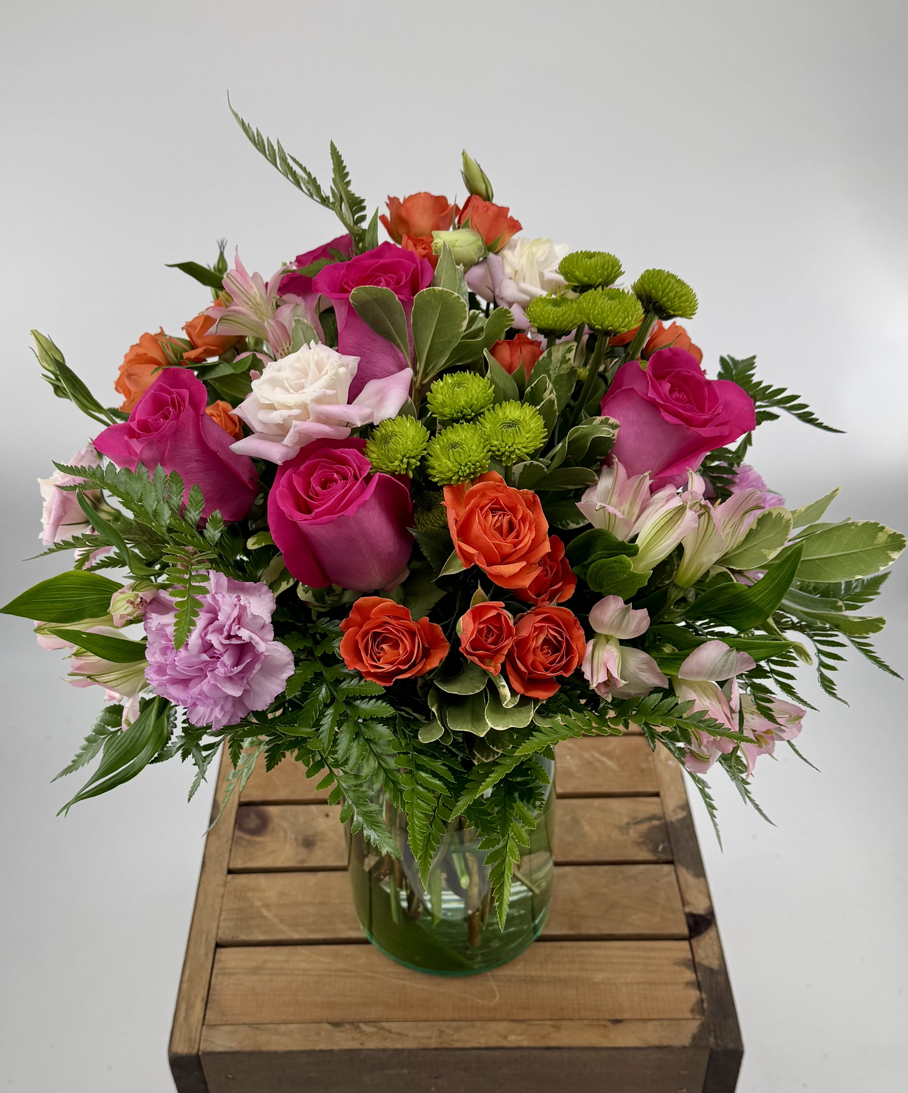 Dreaming (BR) - Indulge in the vibrant hues of our Orange, Pink, and Hot Pink Flower Arrangement, a stunning ensemble of orange roses, pink lisianthus, orange spray roses, green buttons, and pink carnations. Expertly arranged in a clear glass vase, this captivating medley exudes a perfect blend of warmth and elegance. Elevate any space with this colorful bouquet that promises to brighten every moment.