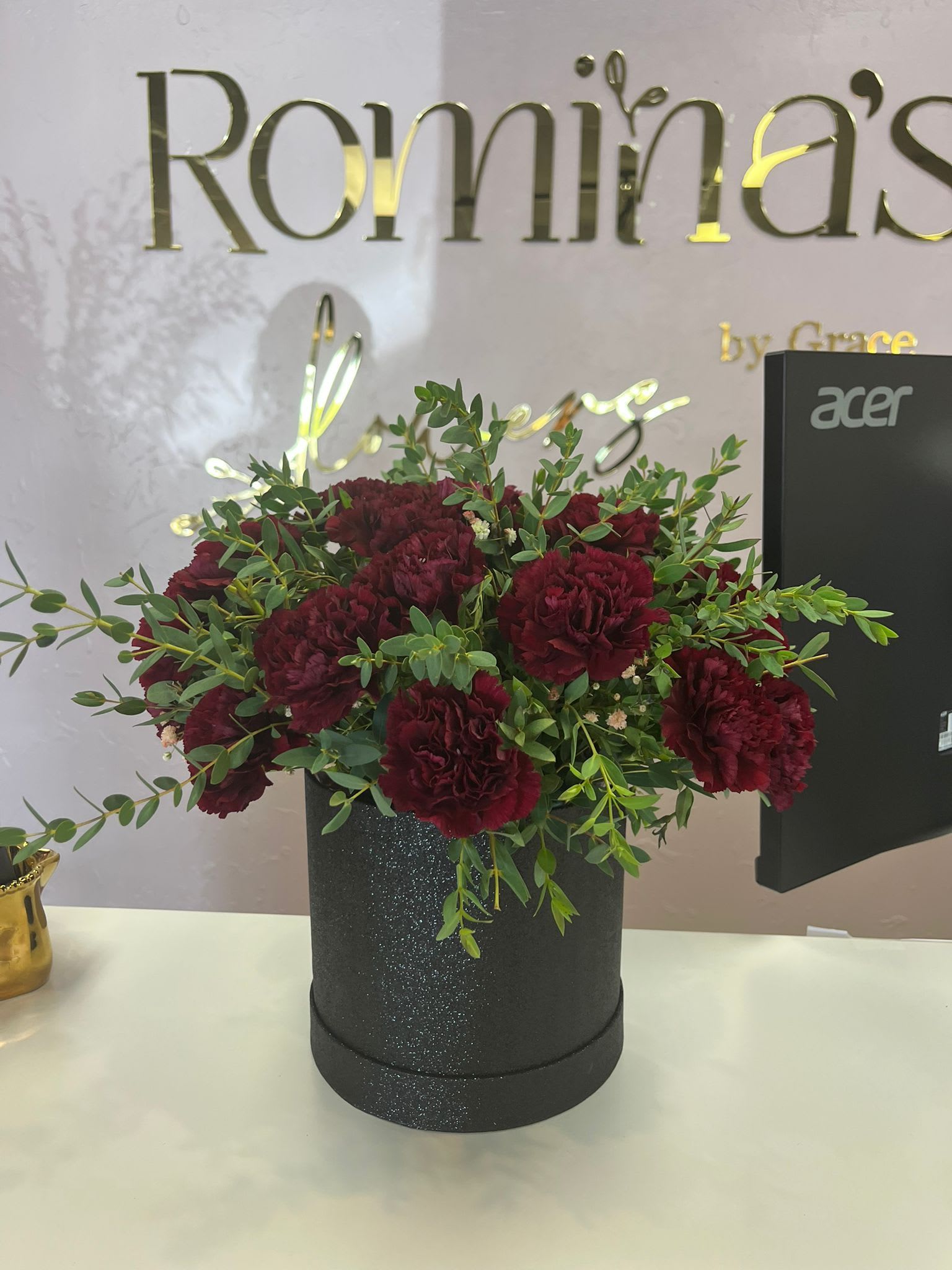 Raquel - &quot;An arrangement of fresh carnations presented on a black cardboard base, highlighting the intensity of their colors and adding a modern and elegant touch. The contrast between the green foliage and the dark base makes each flower stand out, making it ideal for giving with style and distinction.&quot;  &quot;Arreglo de claveles frescos presentado en una base de cartón negro, que resalta la intensidad de sus colores y aporta un toque moderno y elegante. El contraste entre el follaje verde y la base oscura hace que cada flor luzca con mayor protagonismo, ideal para regalar con estilo y distinción.&quot;