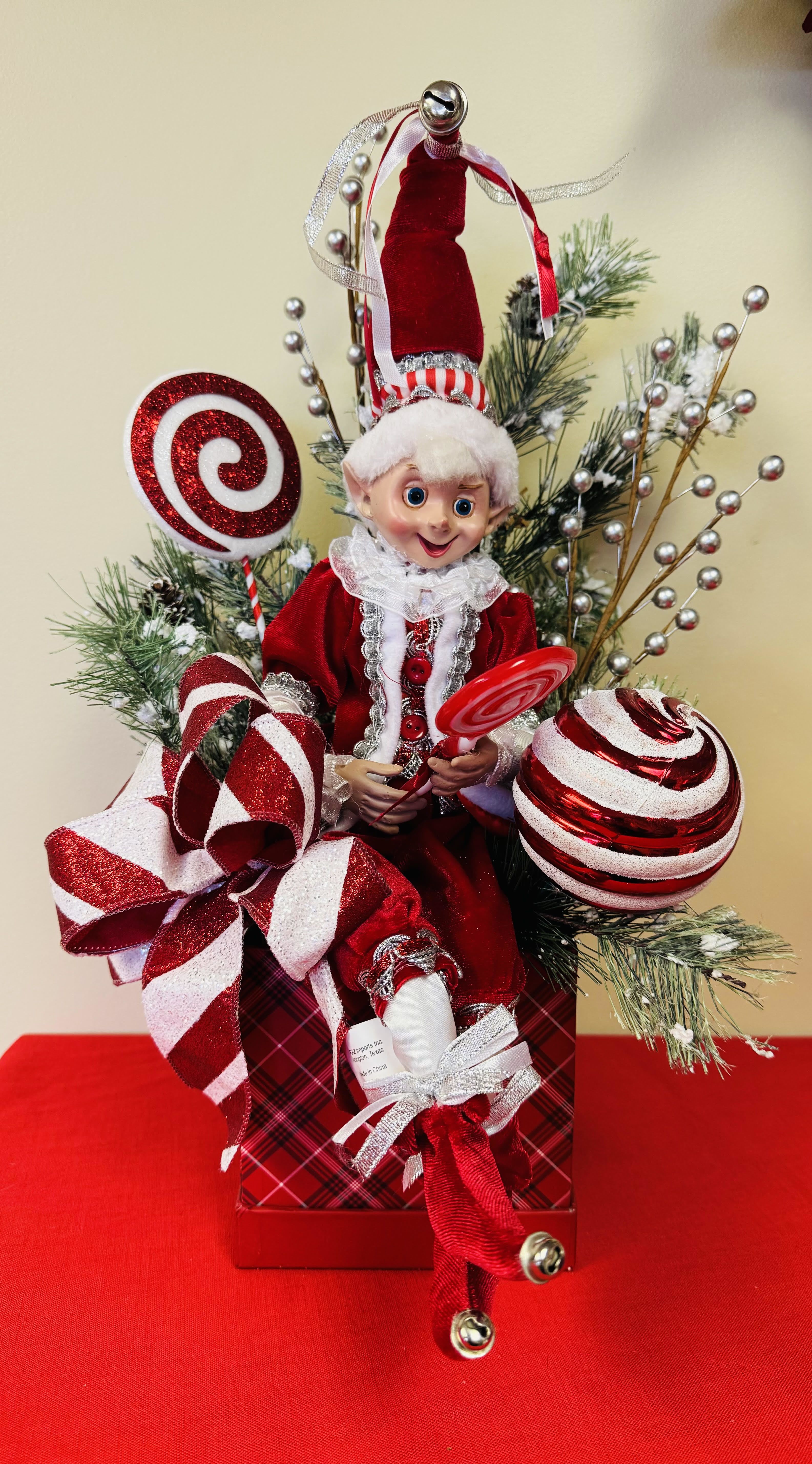 Pepper the Christmas Elf Pepper the Christmas Elf - Pepper the Elf is a adorable Elf Centerpiece just waiting to go to someone's home for the Christmas holidays. Definitely would look great as a centerpiece, on someone's side table or even decorate in a child's room. Made in a red christmas square hatbox that is loaded with christmas greenery, a red & white bow and christmas decor. 19 inches high by 12 inches wide
