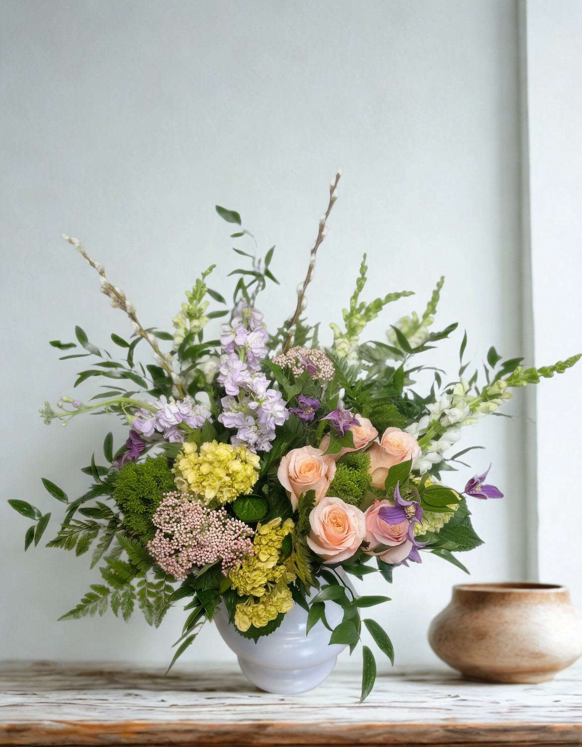 Pastel Sympathy Gathering  - A soothing collection of seasonal blooms in pastel shades gather to create a stunning piece for the funeral home or gravesite. Flowers may include roses, hydrangea and delphinium but will vary based on seasonality.  Approx. 30&quot; Tall x 18&quot; Wide 