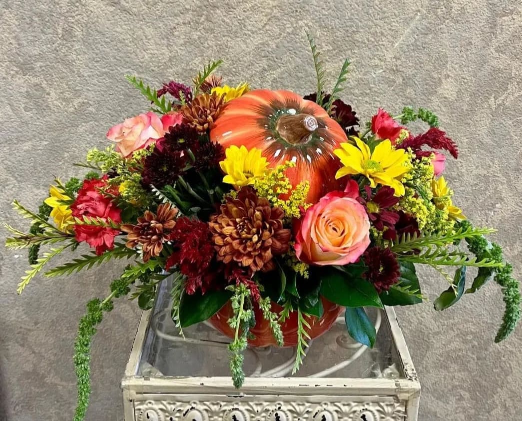 Pumpkin to my Pie in Cookie Jar - Type of Flowers:  Fall Daisies, Orange Roses, Dahlias, Pink Alstroemerias, and Peach Mini Carnations, and Dusty Miller in a short pumpkin, ceramic cookie jar pot with lid. Availability: All year round Substitute Available: Yes Design View: Symmetric Front Facing View Photo shown: Regular