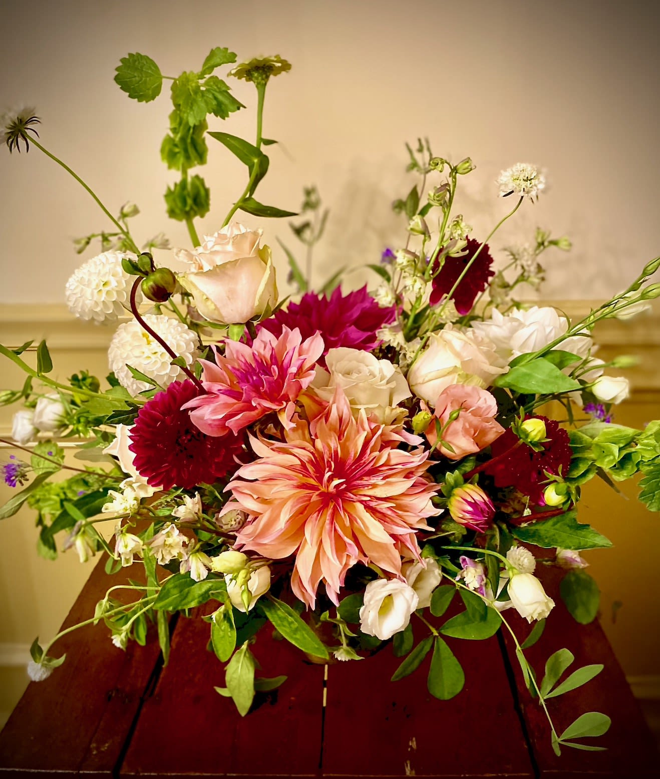 October Romance- SOLD OUT - October Romance is a captivating fall flower arrangement that captures the warmth and richness of the autumn season. The arrangement features bold dahlias in shades of deep burgundy, burnt orange, and golden yellow, symbolizing the passionate beauty of fall. Interspersed among the dahlias are clusters of vibrant gomphrena, their round, textured blooms adding a playful yet elegant touch. Exotic greens, with their lush and varied textures, create a striking contrast, bringing a sense of wild, natural beauty to the composition. The &quot;October Romance&quot; arrangement evokes the crisp air and vibrant colors of autumn, making it an ideal choice for adding a touch of seasonal charm to any space or as a thoughtful gift that celebrates the romance of the season.