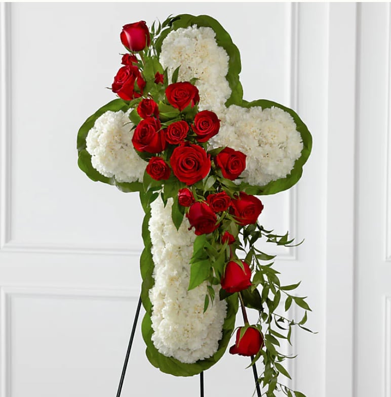 Faithful Remembrance Faithful Remembrance - The Faithful Remembrance is a striking tribute featuring an all-white floral cross symbolizing peace and purity, adorned with a bold cascade of red roses to represent enduring love and sacrifice. A powerful and graceful expression of faith and heartfelt sympathy.