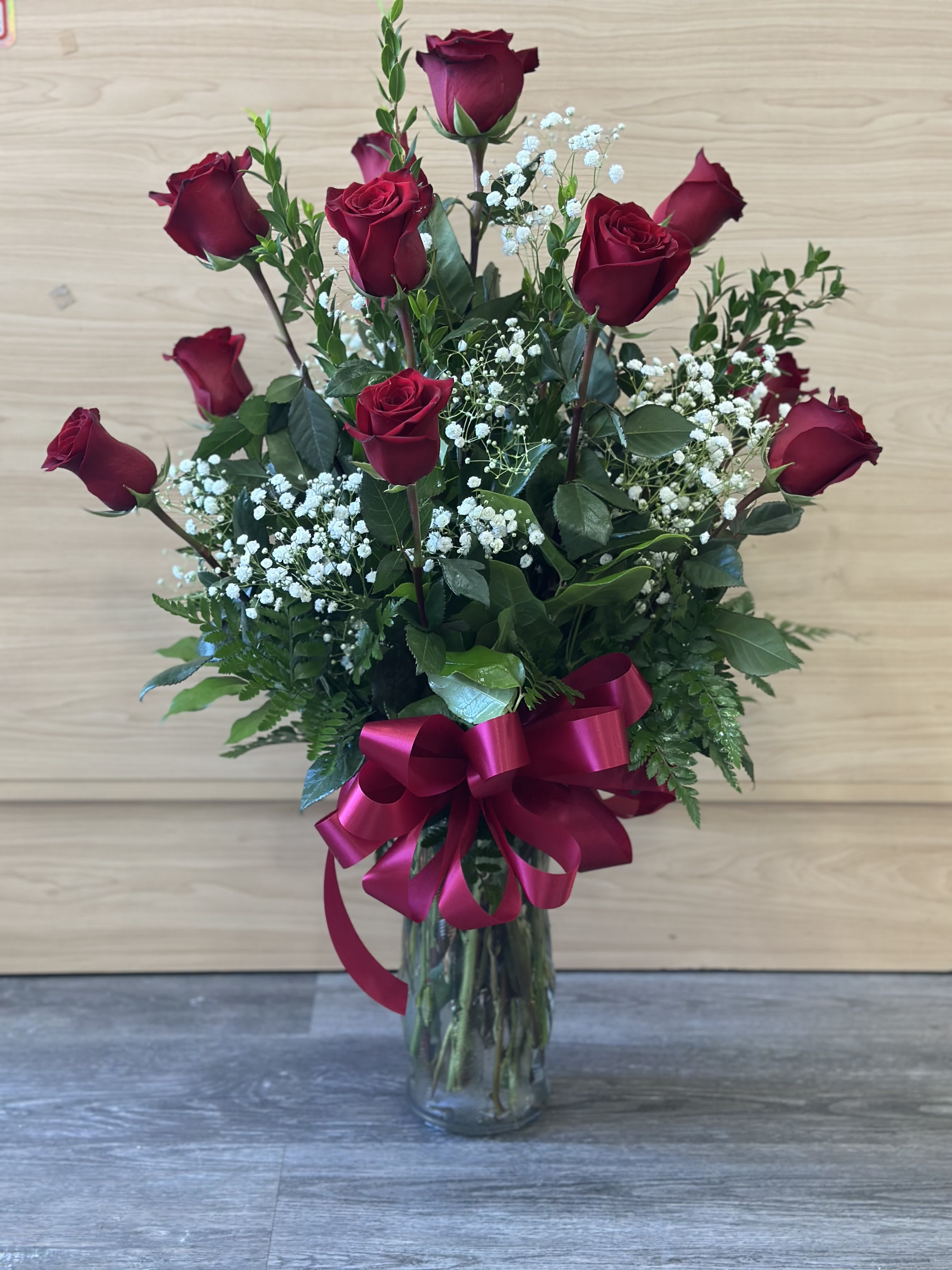 One dozen long stem red velvet roses  One dozen long stem red velvet roses  - 12 long stem dark red roses arranged in a tall clear vase .