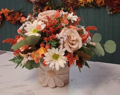 Autumn Daisy Delight - Celebrate the warmth of fall with this charming arrangement, artfully designed in our signature daisy container. Brimming with seasonal blooms in rich autumn hues, it’s a perfect blend of cozy and cheerful — just like the season itself! Please note: flower varieties may vary based on seasonal availability, but we’ll ensure your arrangement is equally stunning and full of fall charm.