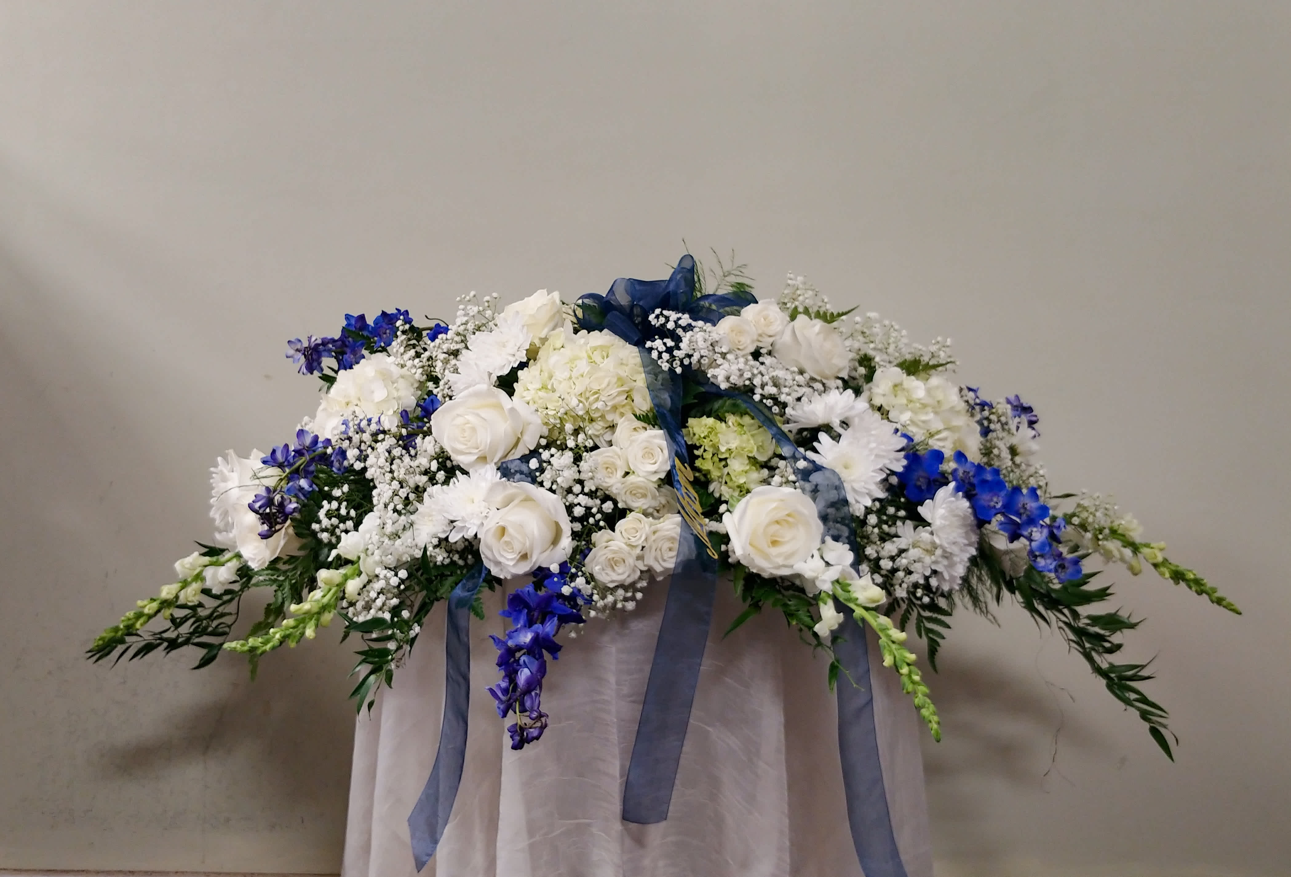 White and Blue Casket Spray White and Blue Casket Spray - A traditional style casket spray featuring white and blue flowers.